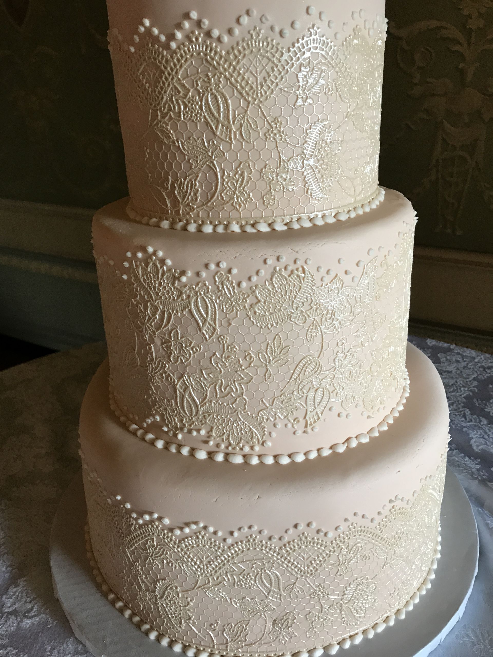 a wedding cake with lace and pearls on it