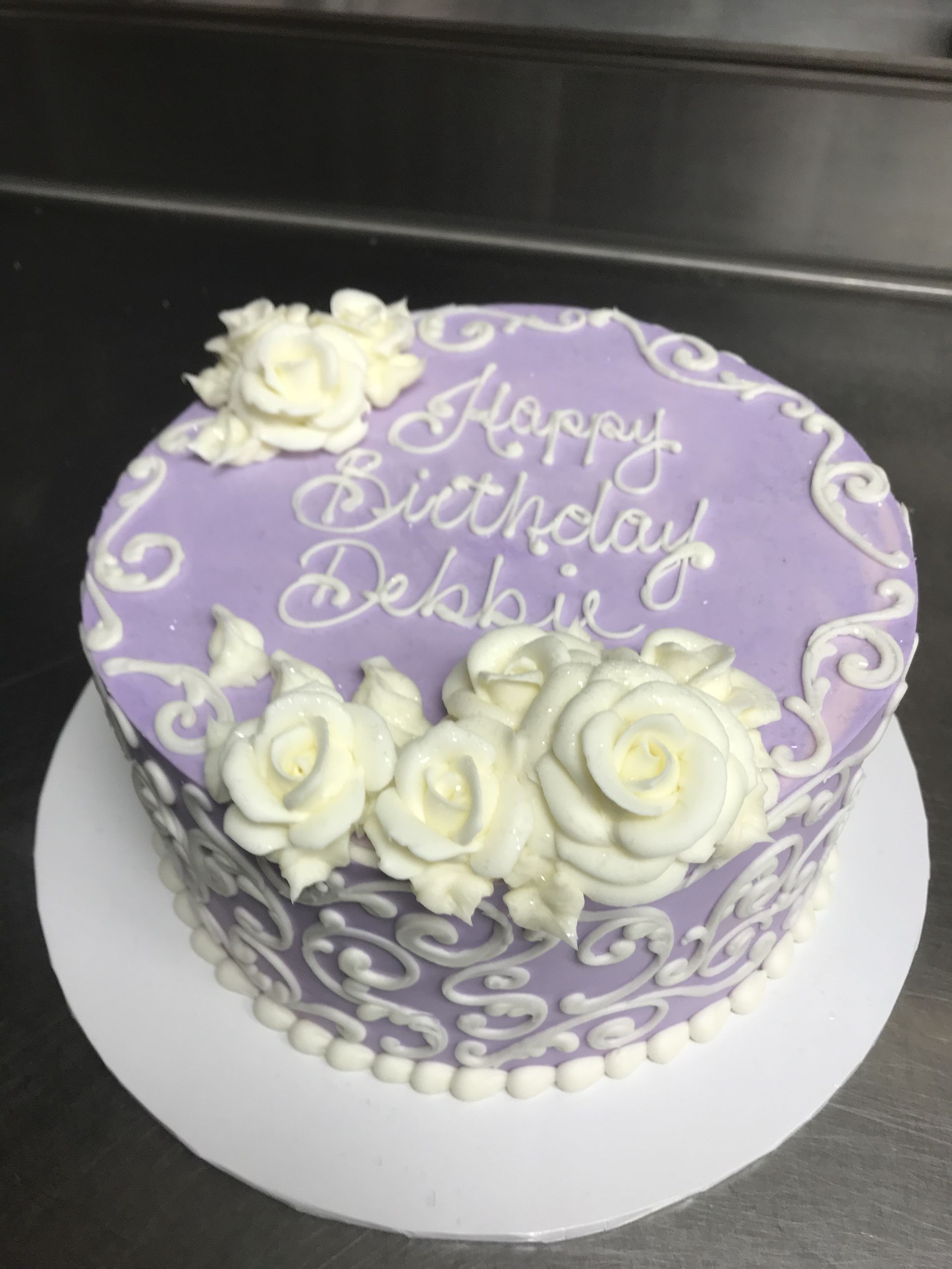 a purple birthday cake with white roses on it