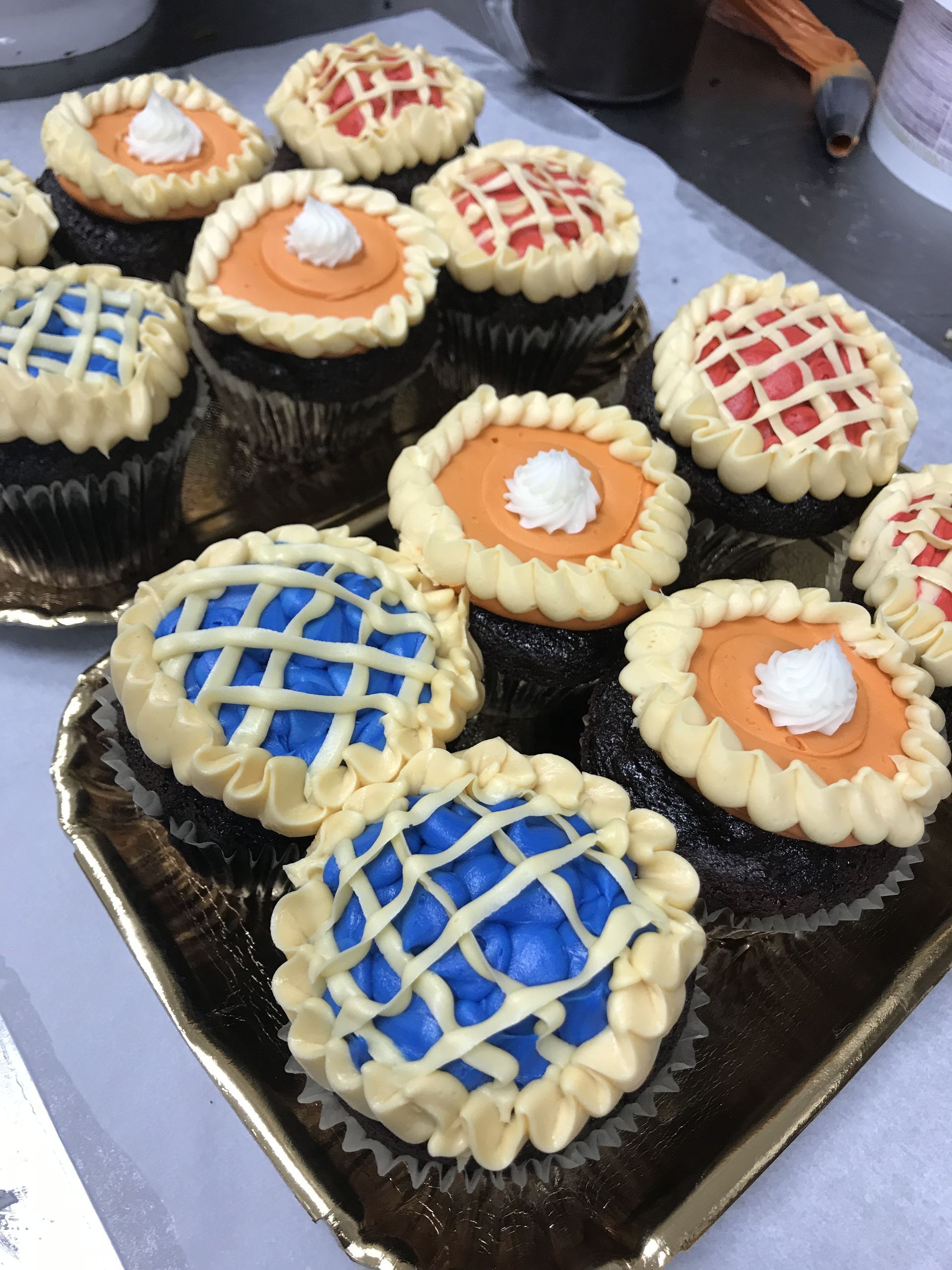 a tray of cupcakes with different colored frosting on them