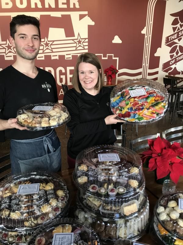 a man and a woman holding trays of food in front of a wall that says burner