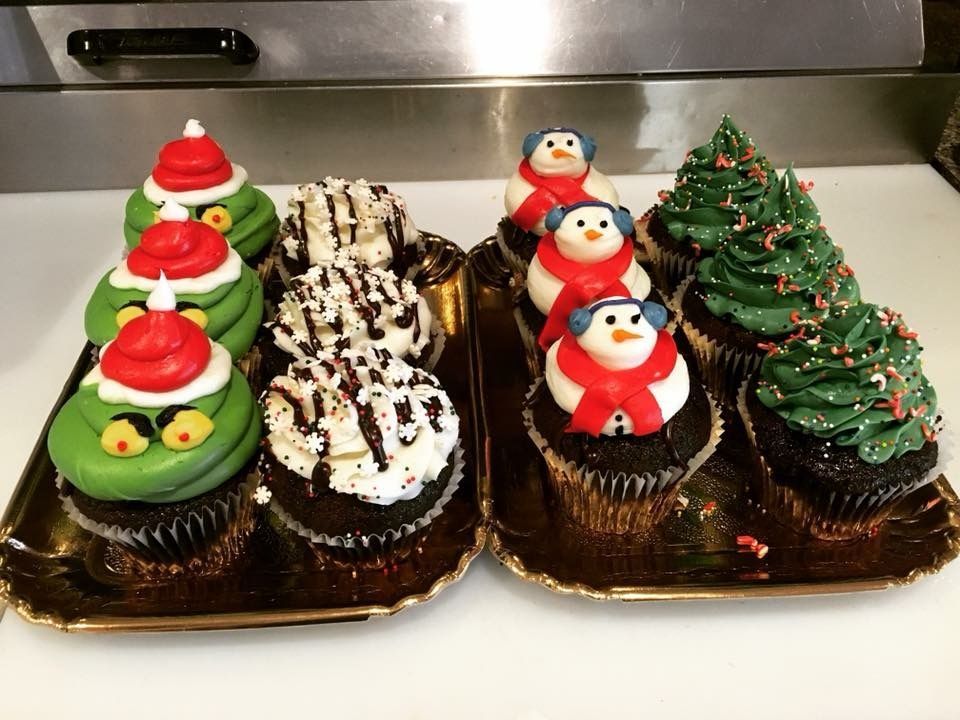 two trays of cupcakes with christmas decorations on them