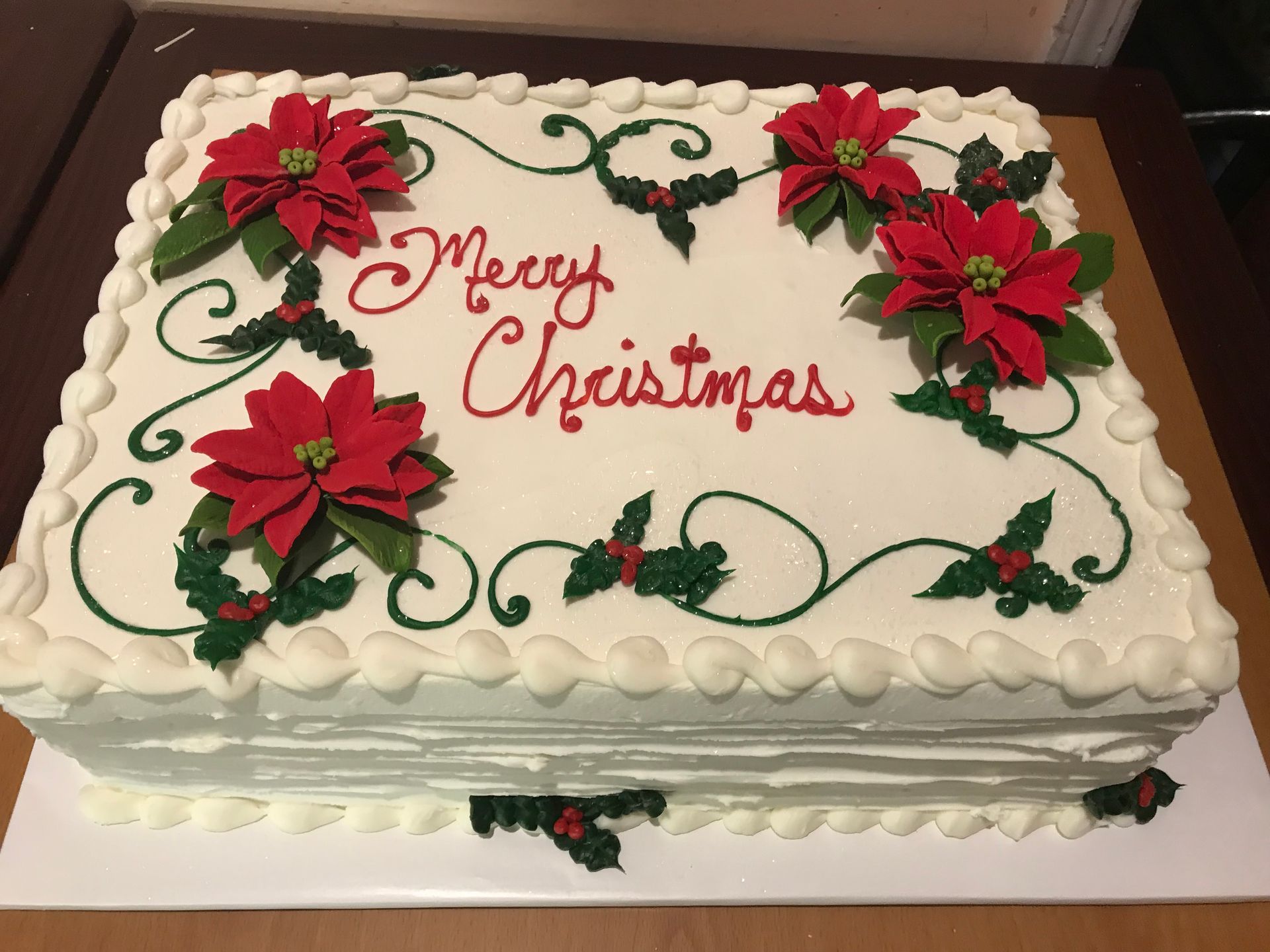 a christmas cake with poinsettia and holly on it