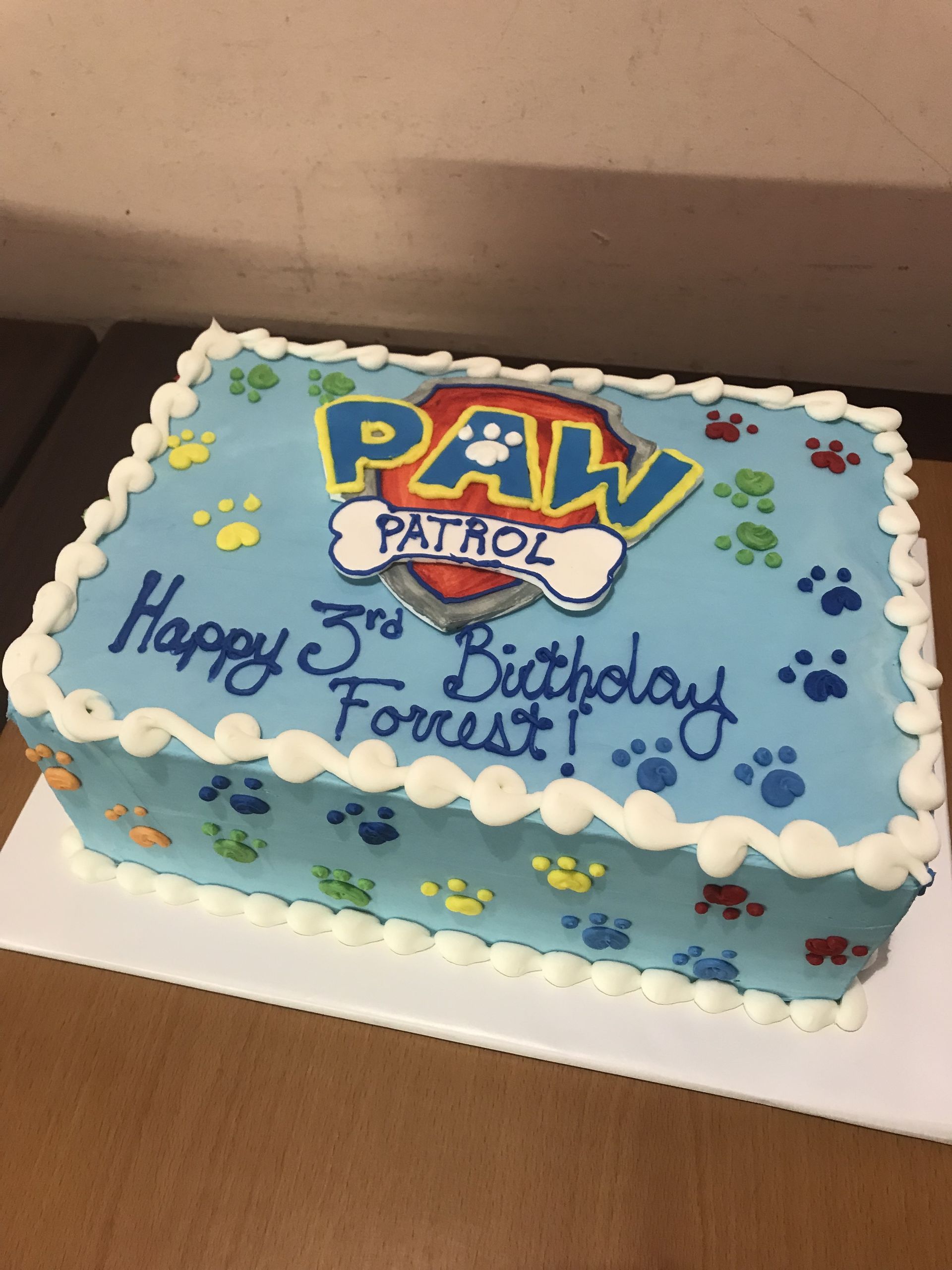 a blue paw patrol birthday cake with paw prints on it