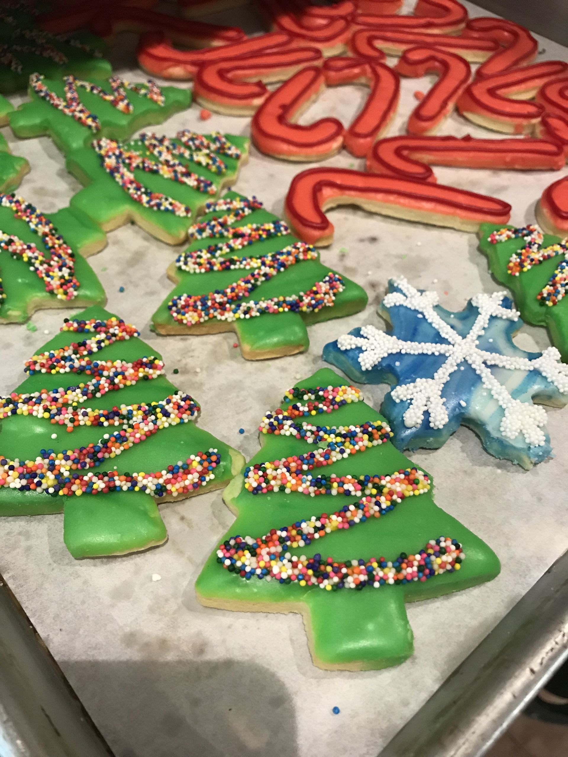 a tray of christmas cookies with green frosting and sprinkles