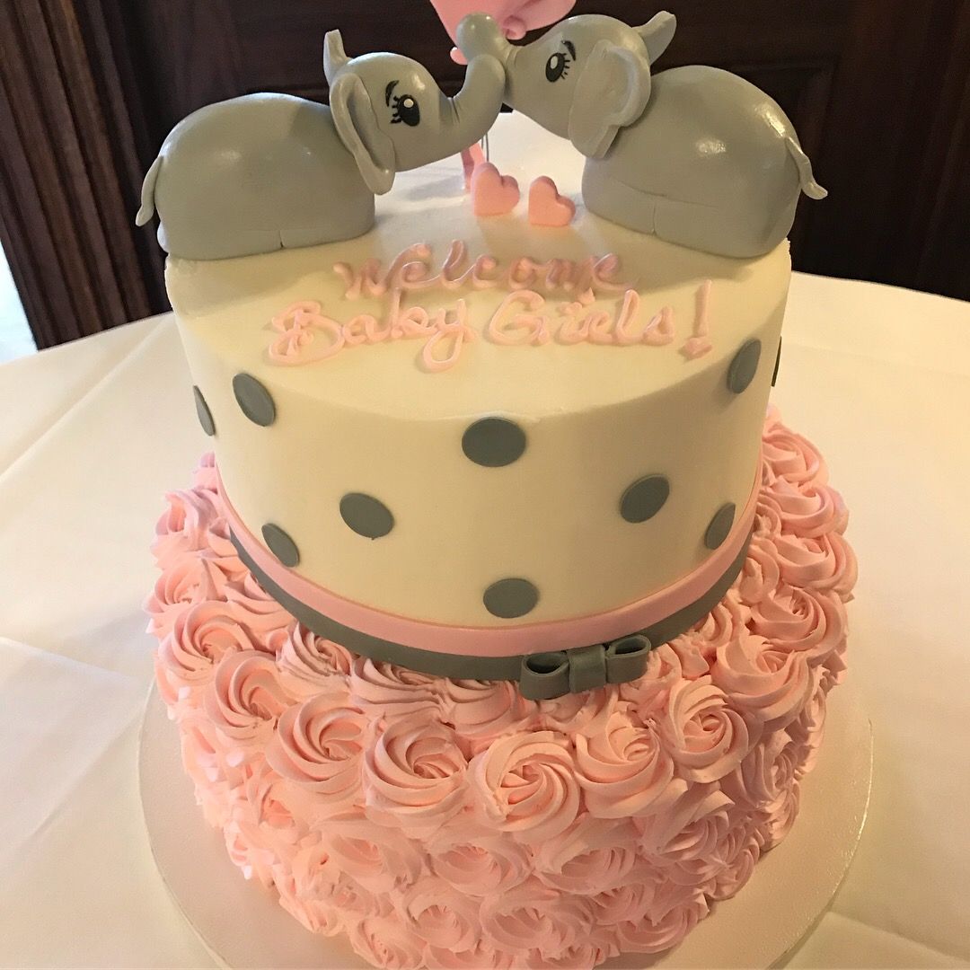a baby shower cake for a girl with two elephants on top