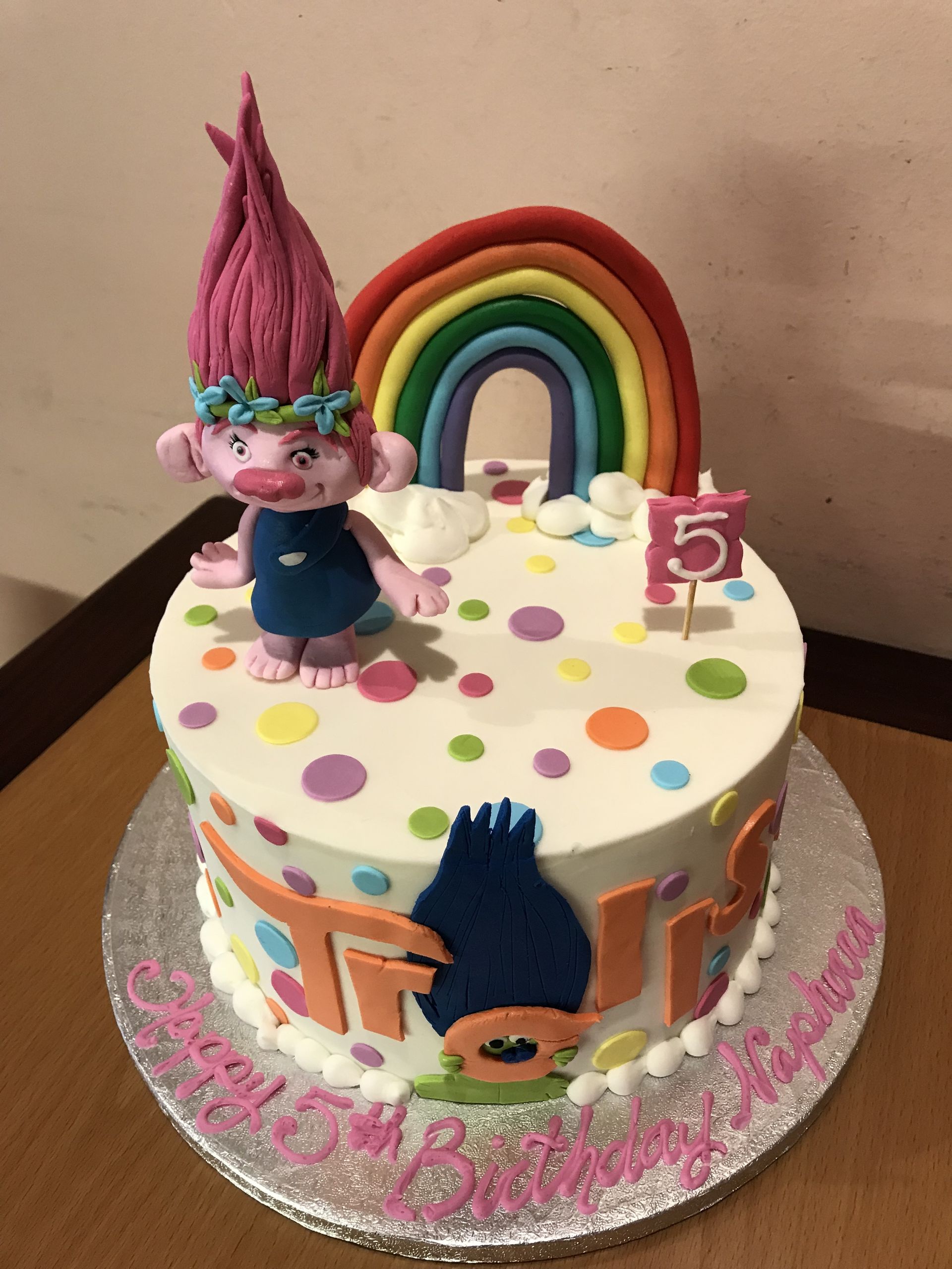 a troll birthday cake with a rainbow and a number 5 candle