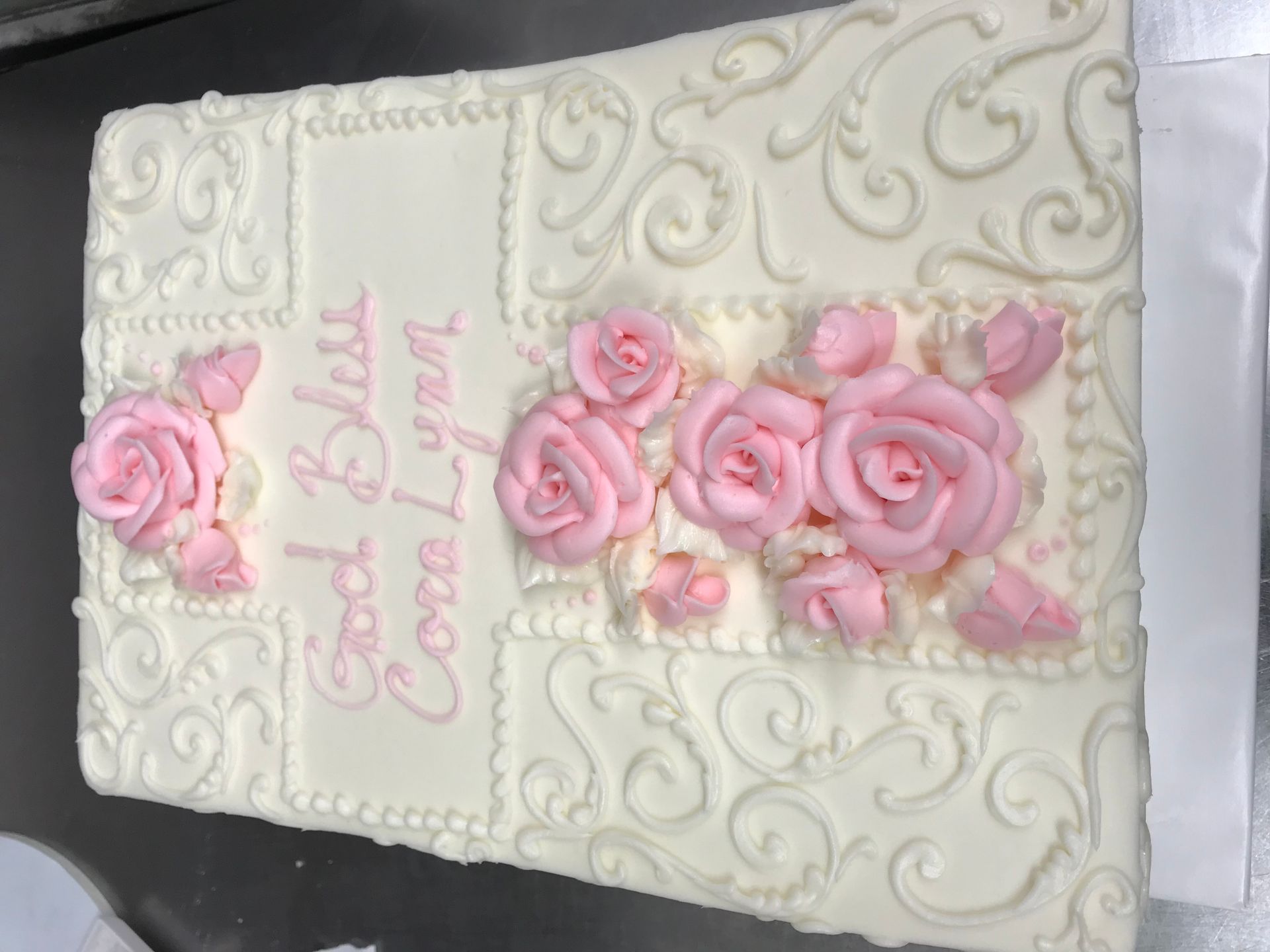 a white cake with pink roses on it is sitting on a table .