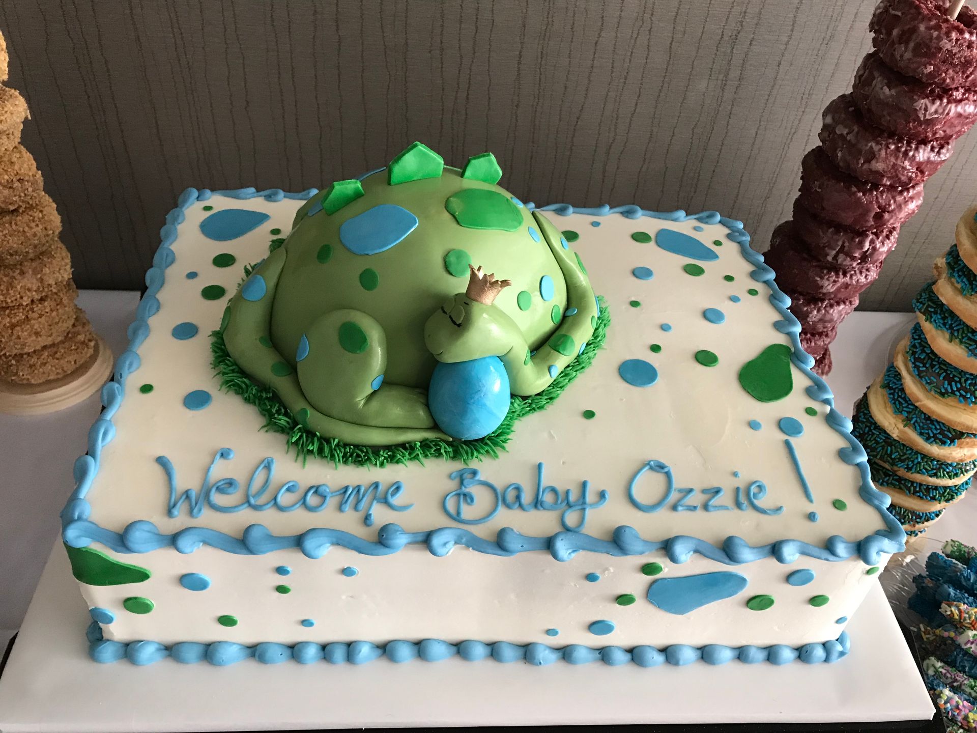 a baby shower cake with a dinosaur and the words welcome baby ozzie