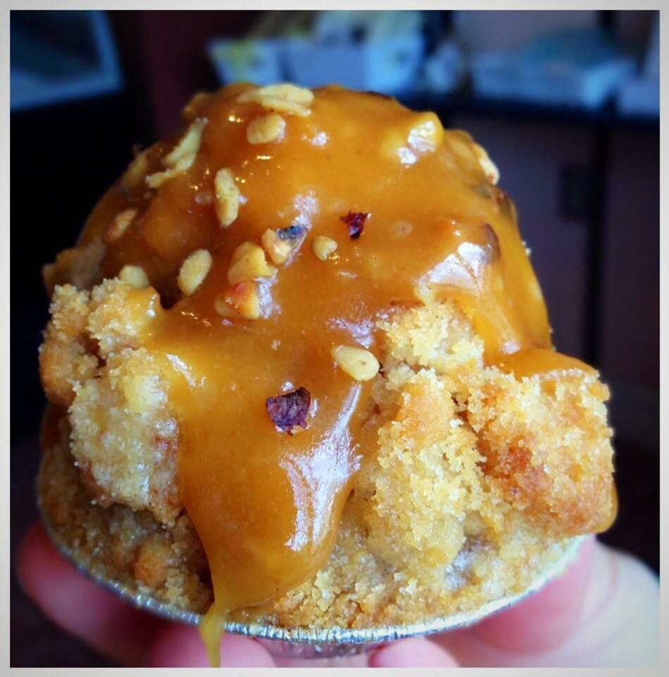 a person is holding a muffin with caramel sauce on top