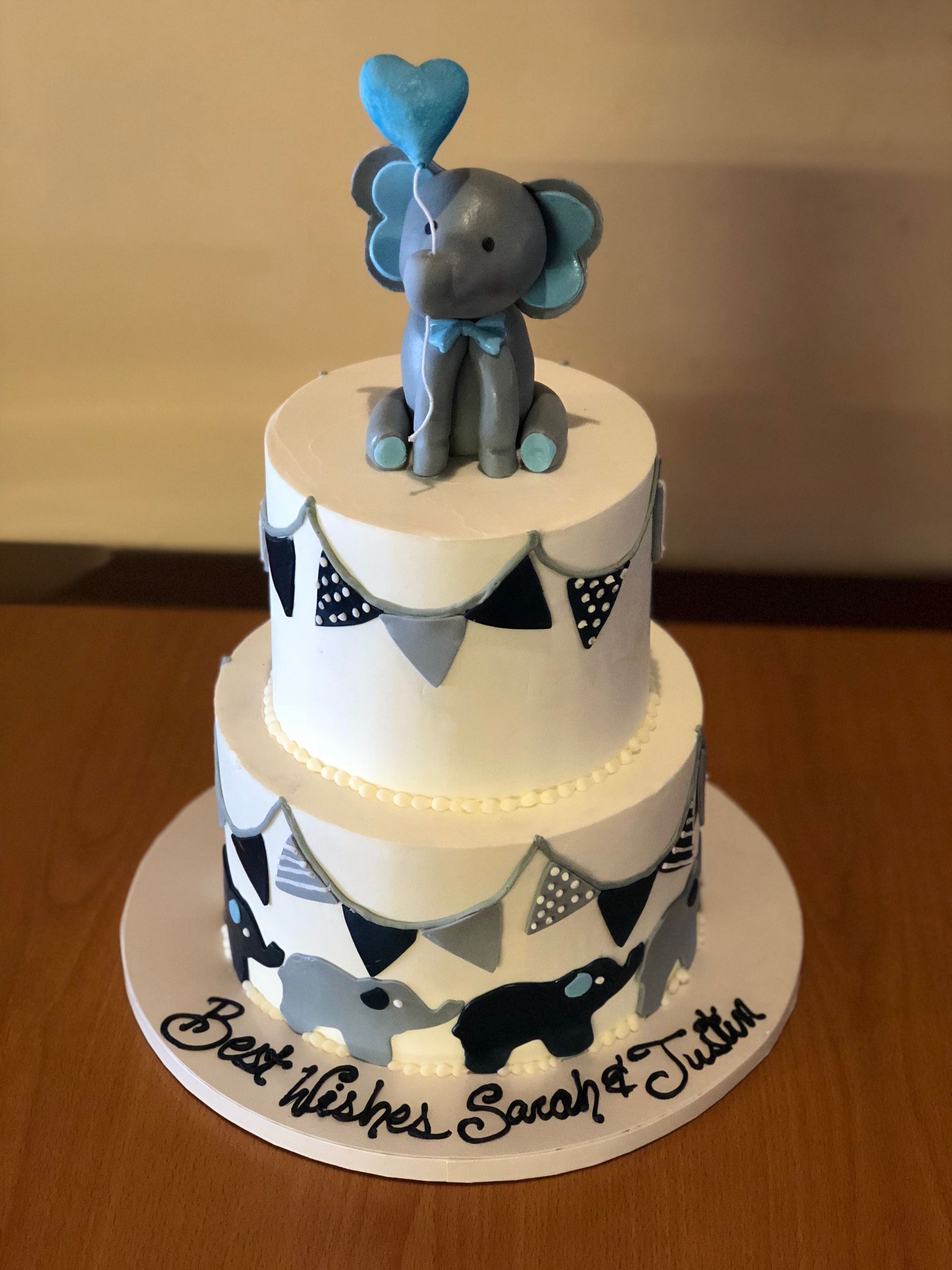 a baby shower cake for sarah and justin with an elephant on top