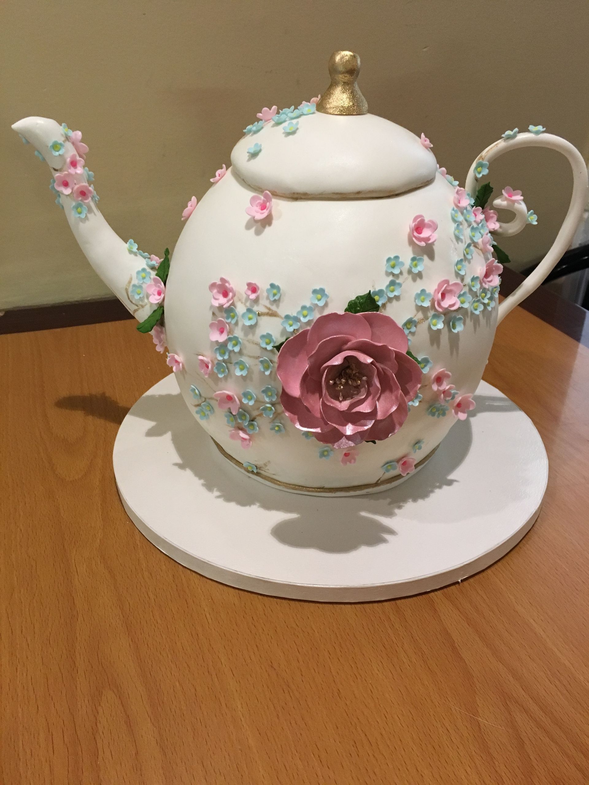 a white teapot decorated with pink and blue flowers