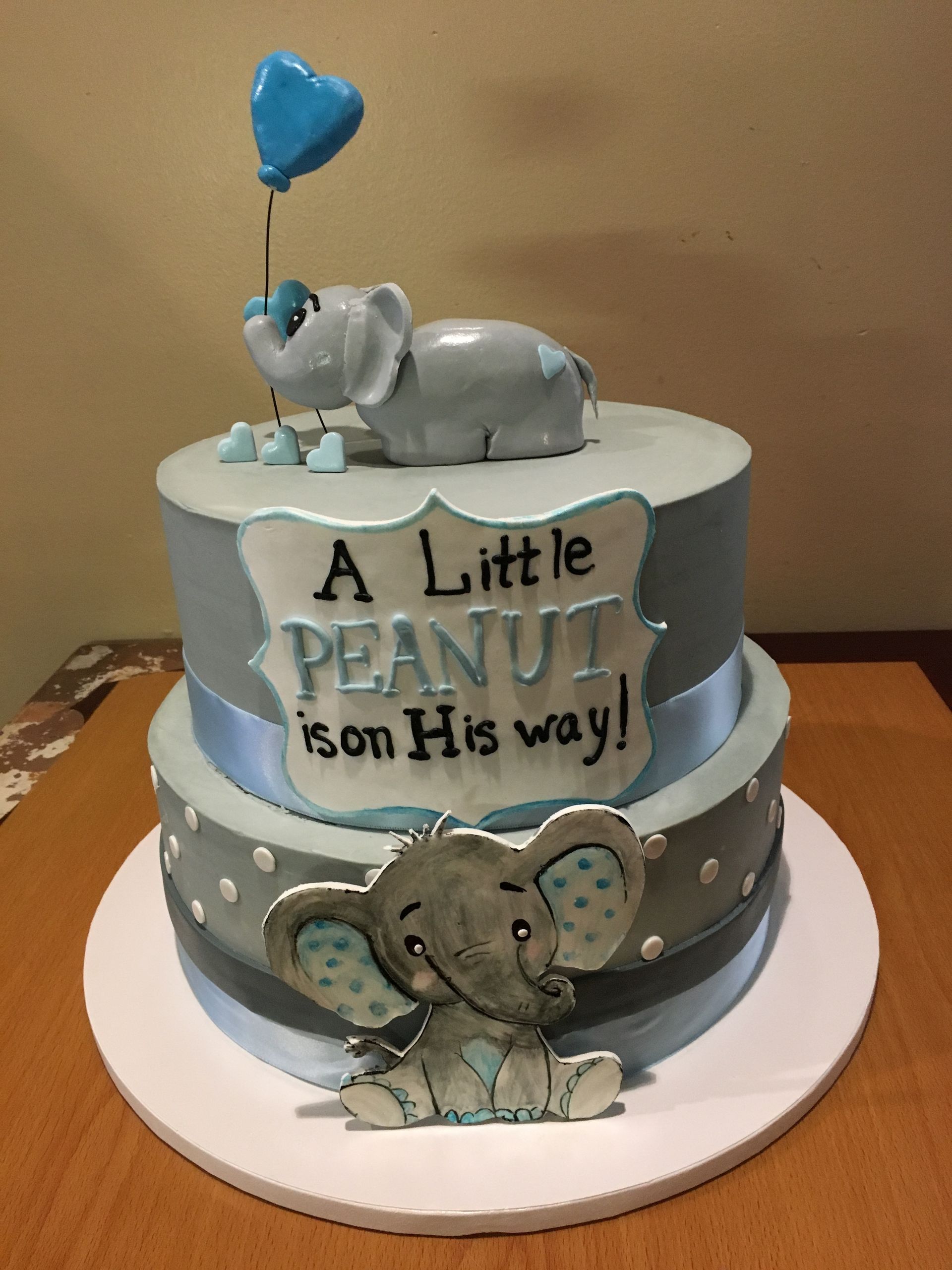 a baby shower cake with an elephant holding a heart shaped balloon