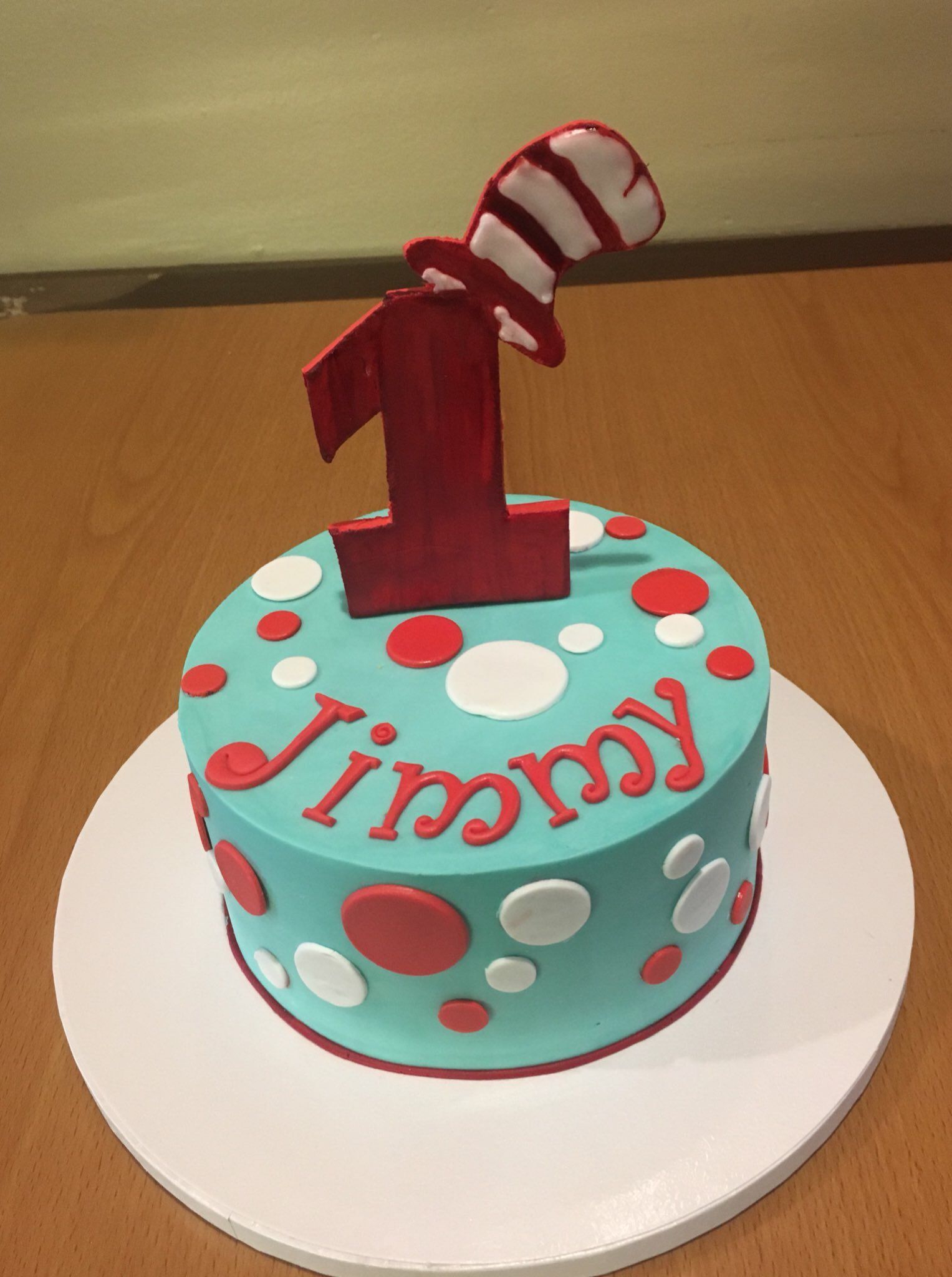 a first birthday cake for jimmy with a cat in the hat on top
