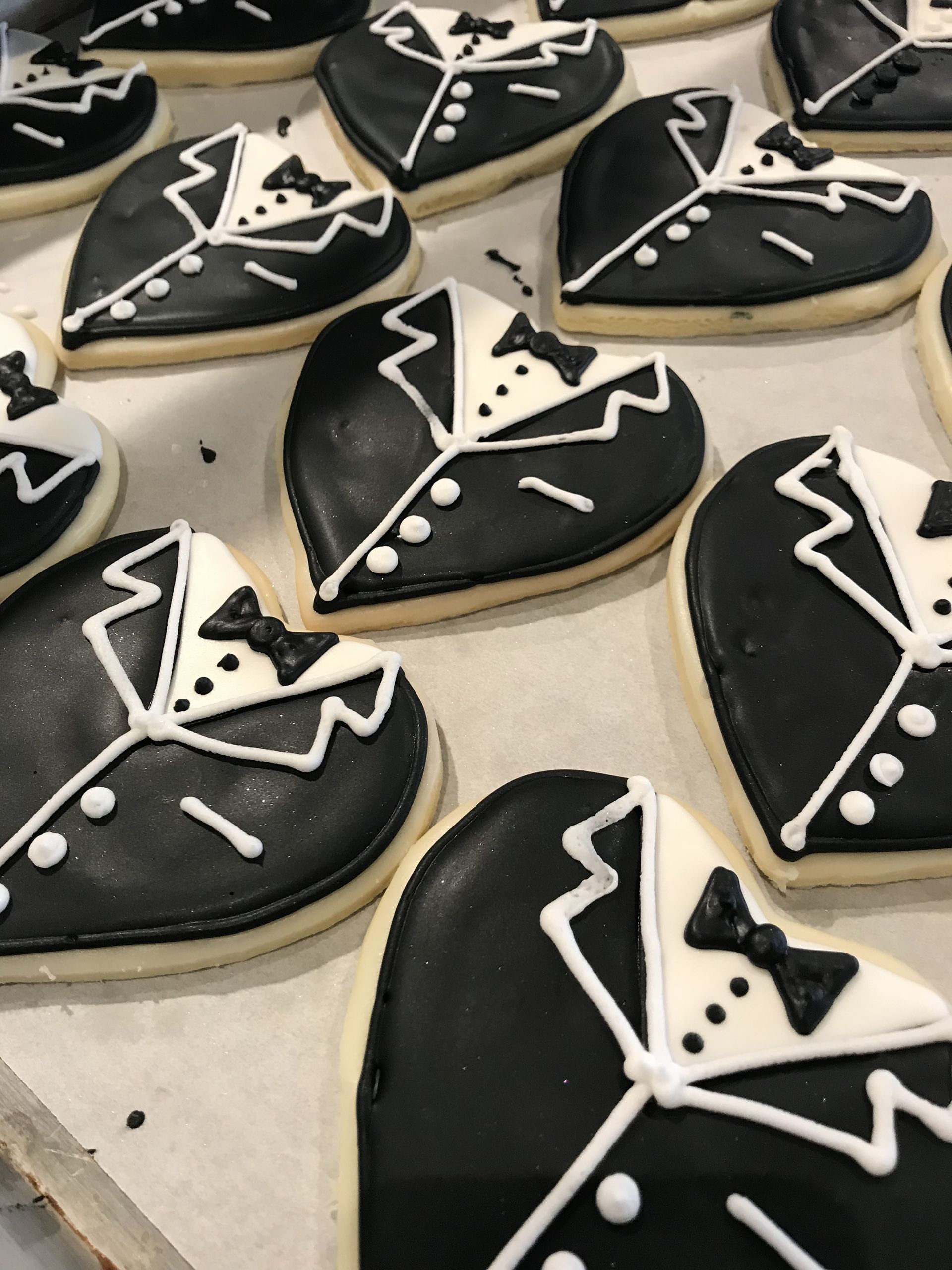 a bunch of black and white heart shaped cookies with tuxedos on them