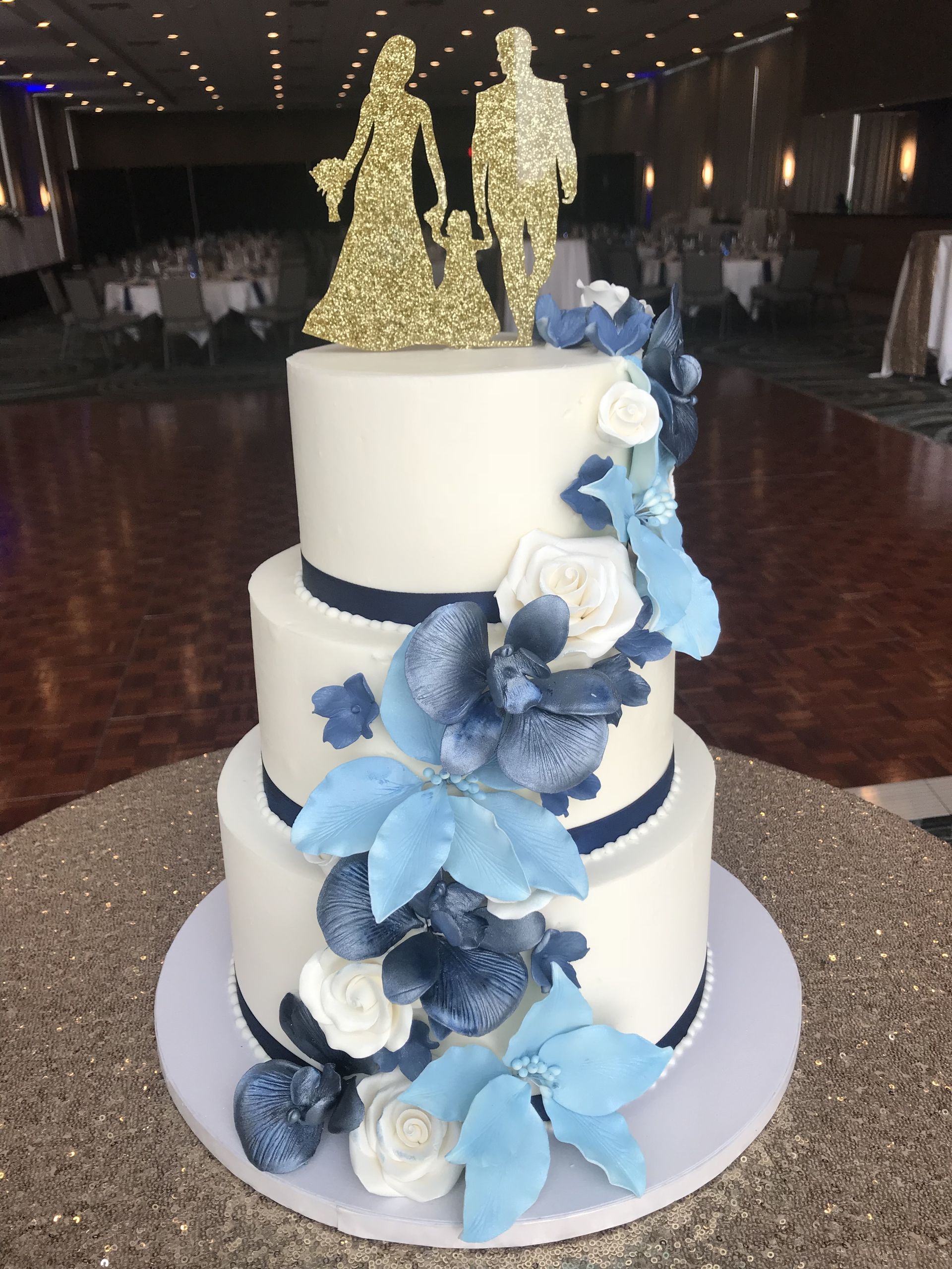 a wedding cake with blue flowers and a bride and groom topper