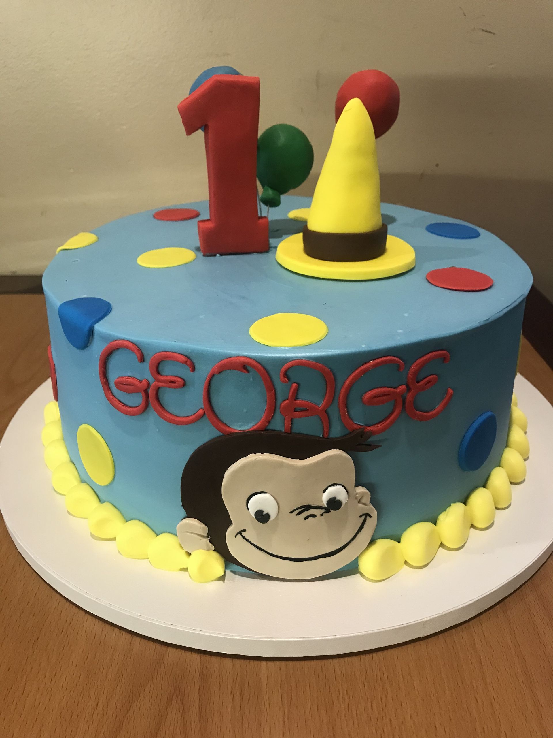 a 1st birthday cake for george with a curious monkey on it
