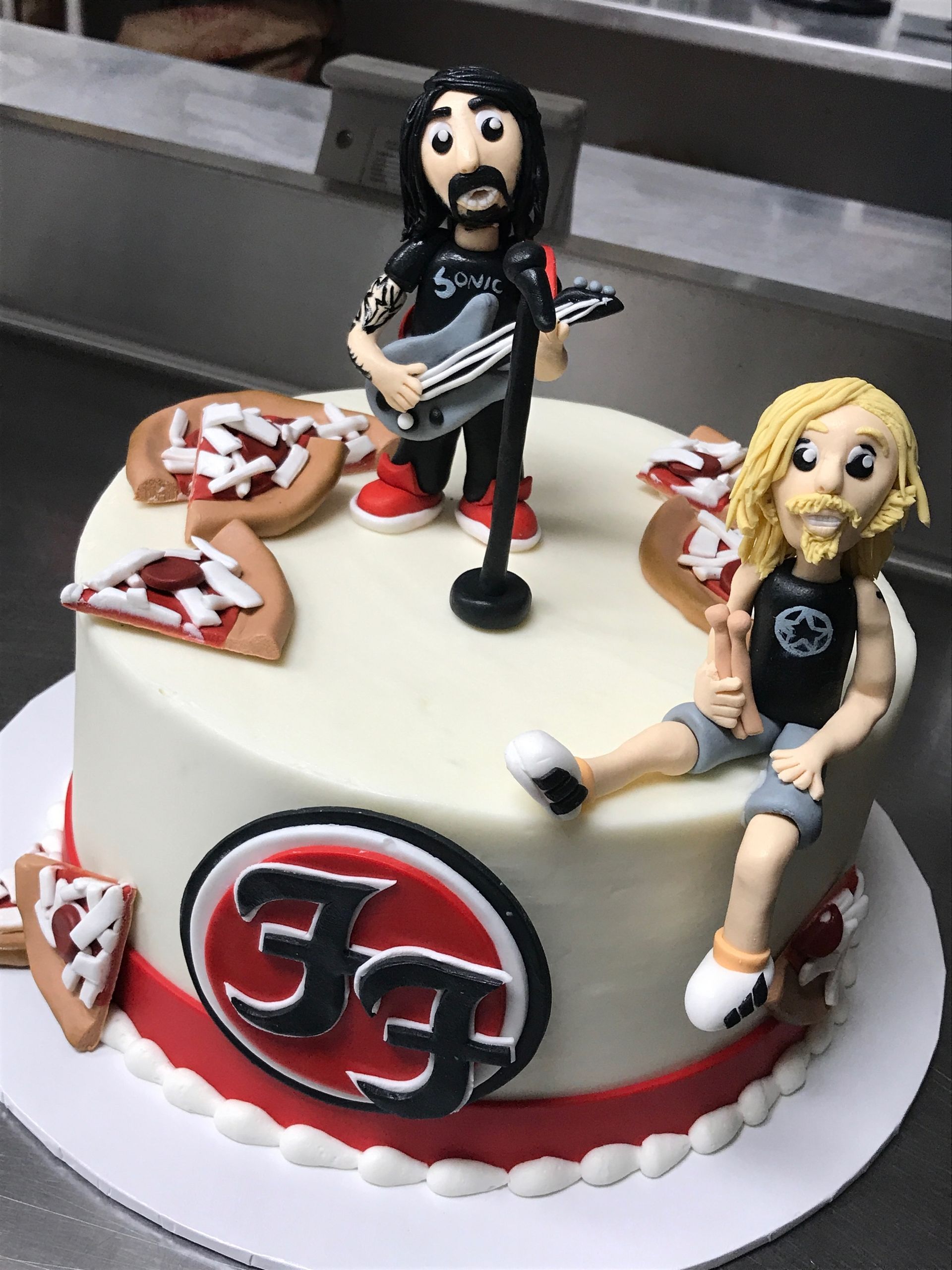 a cake with a man playing a guitar and a woman sitting on it