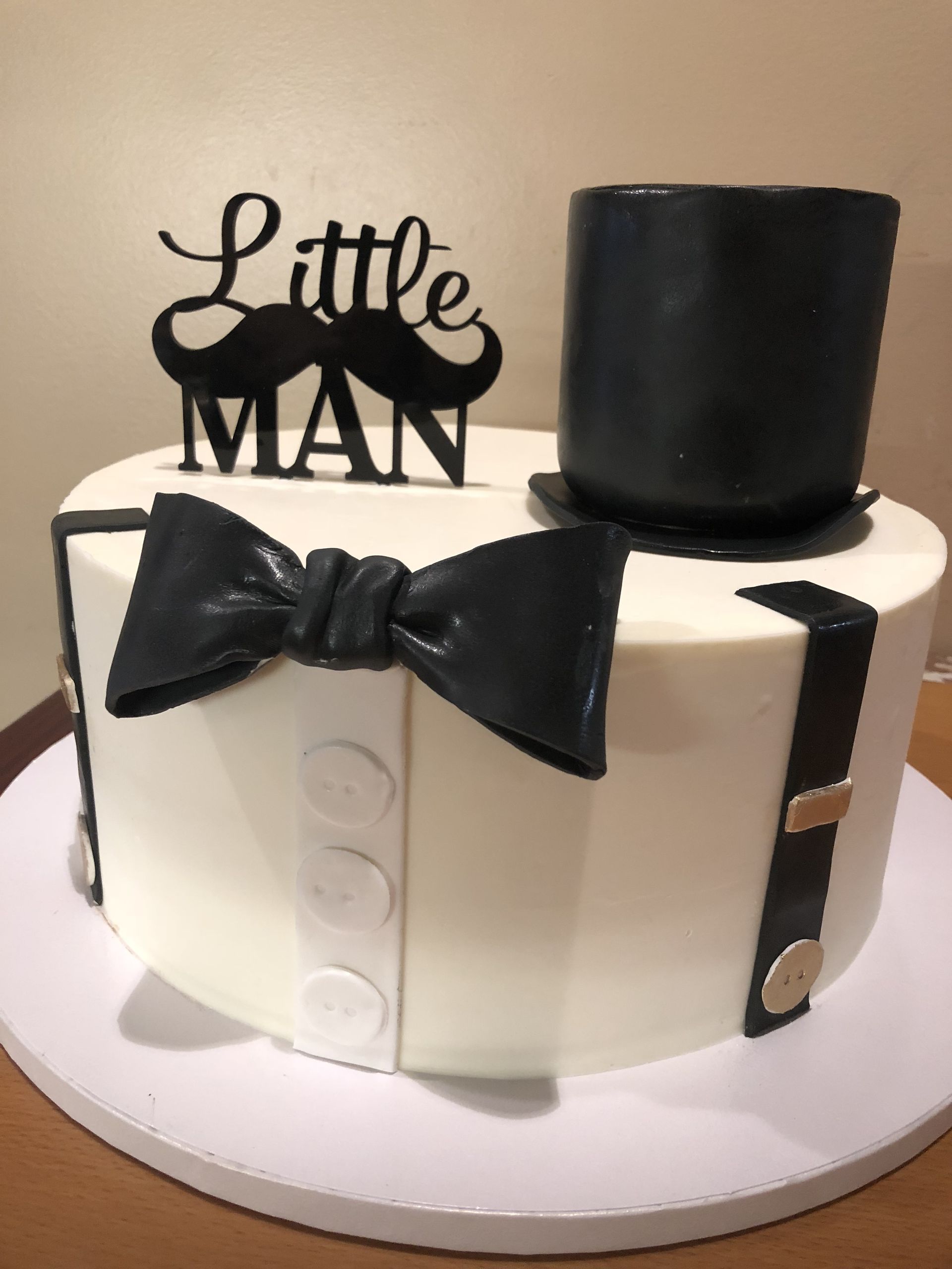 a white cake with a top hat , bow tie and mustache on it .