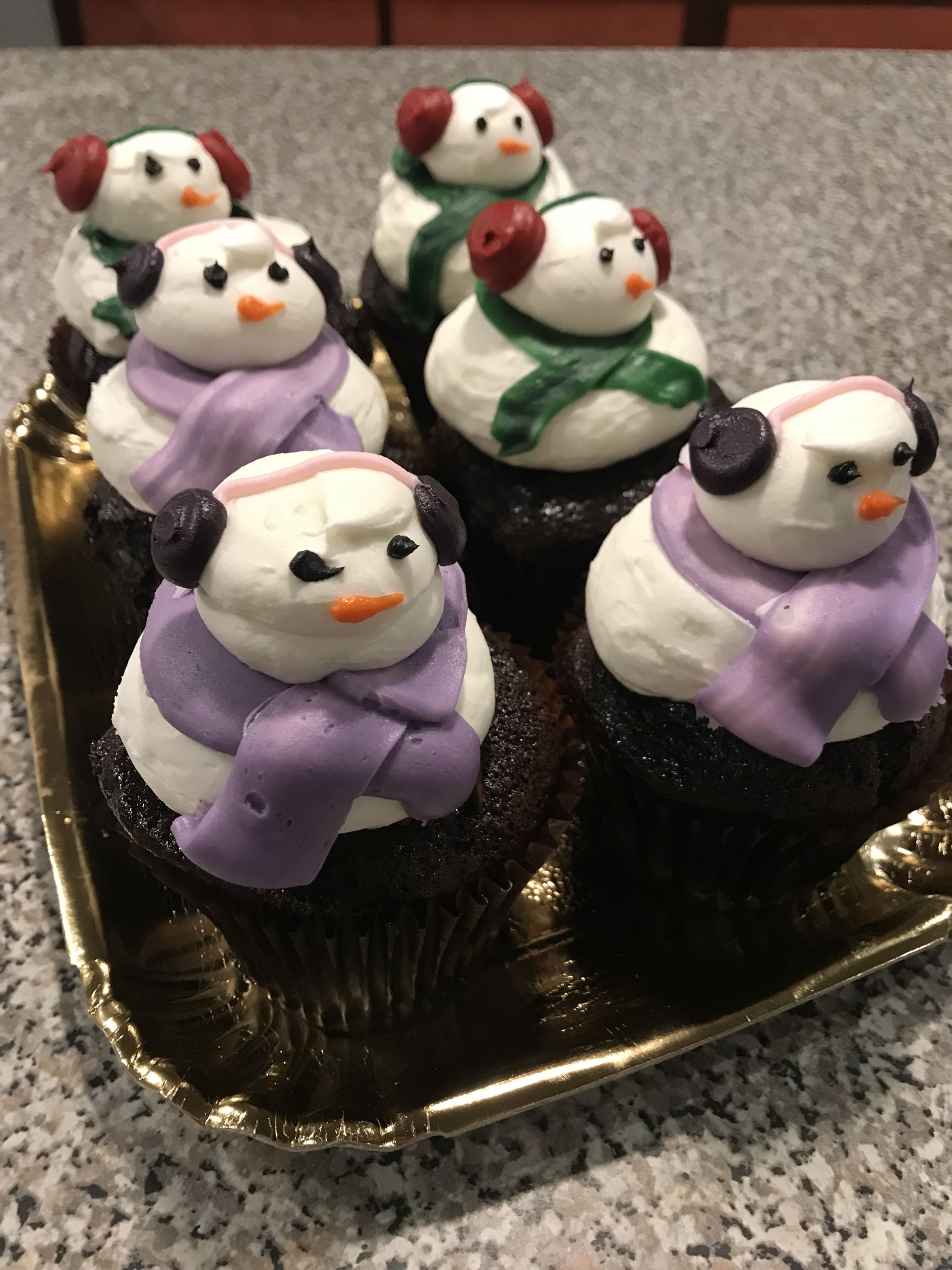a tray of chocolate cupcakes decorated to look like snowmen
