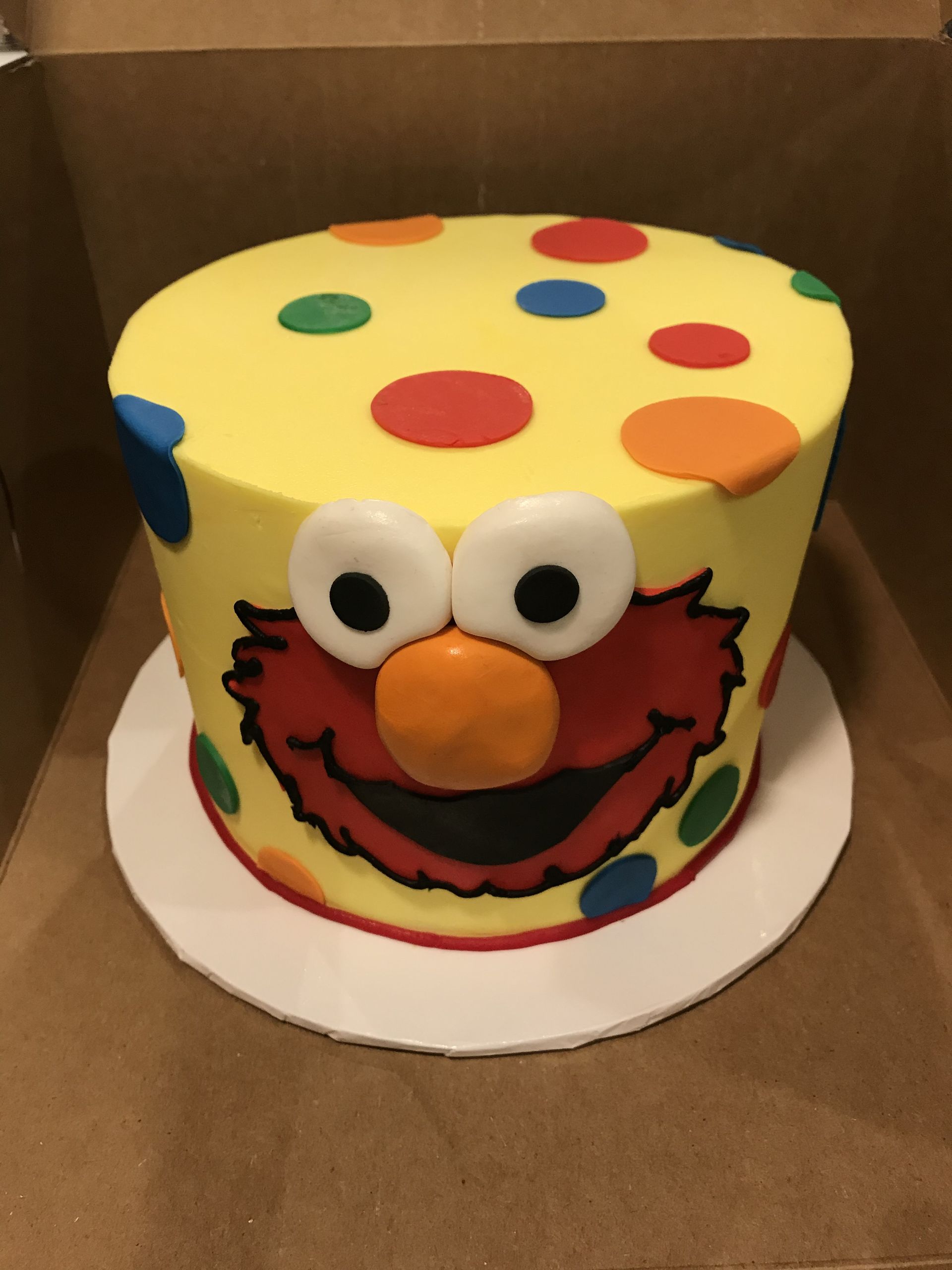 a yellow cake with elmo on it is in a box