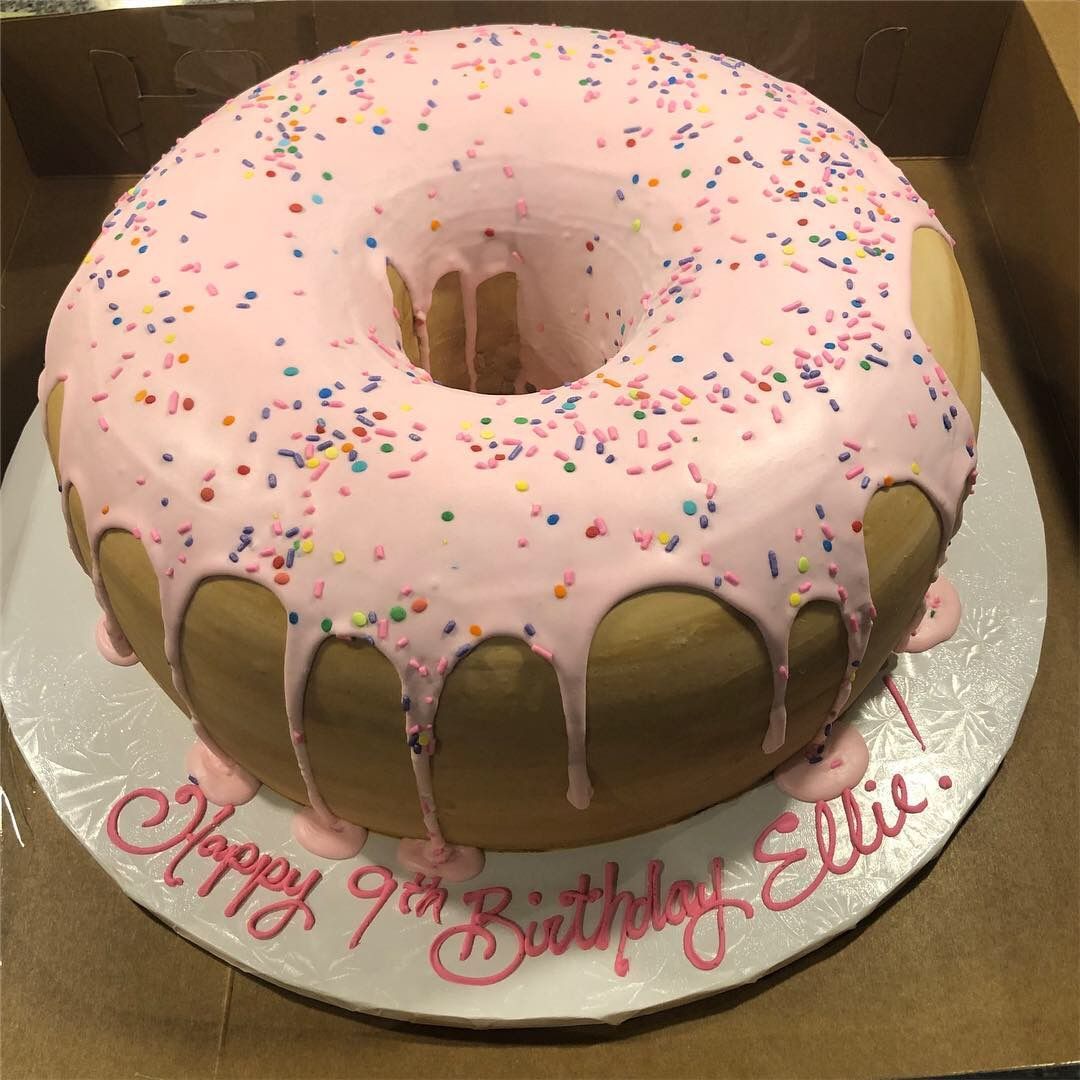 a donut cake with pink frosting and sprinkles for ellie 's 9th birthday