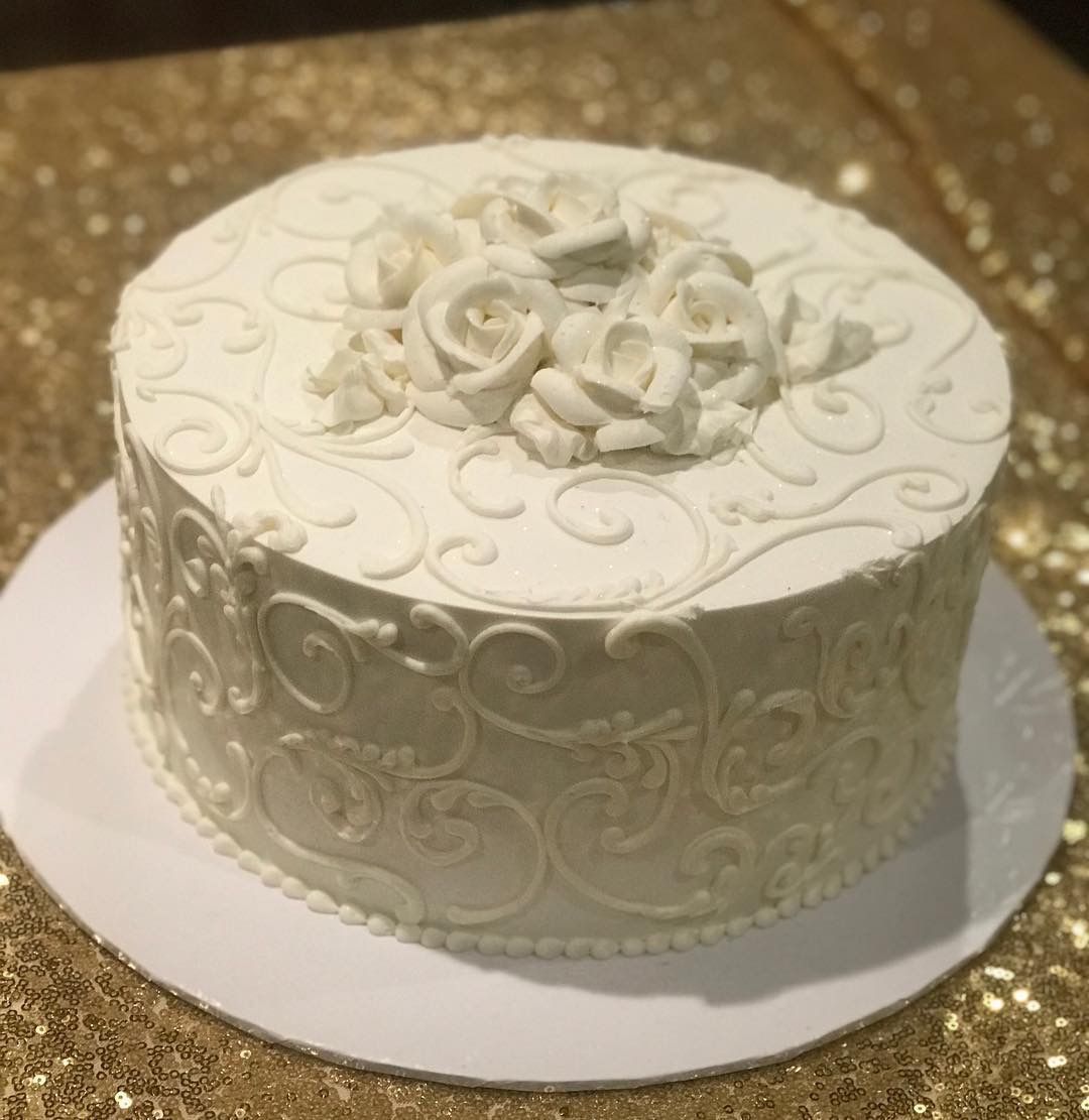 a white cake with roses on top is sitting on a table .