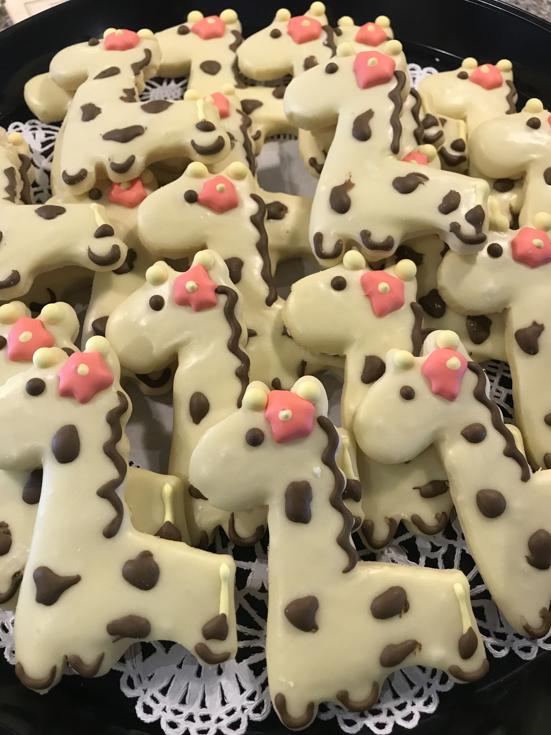 a plate of giraffe shaped cookies with pink bows on their heads