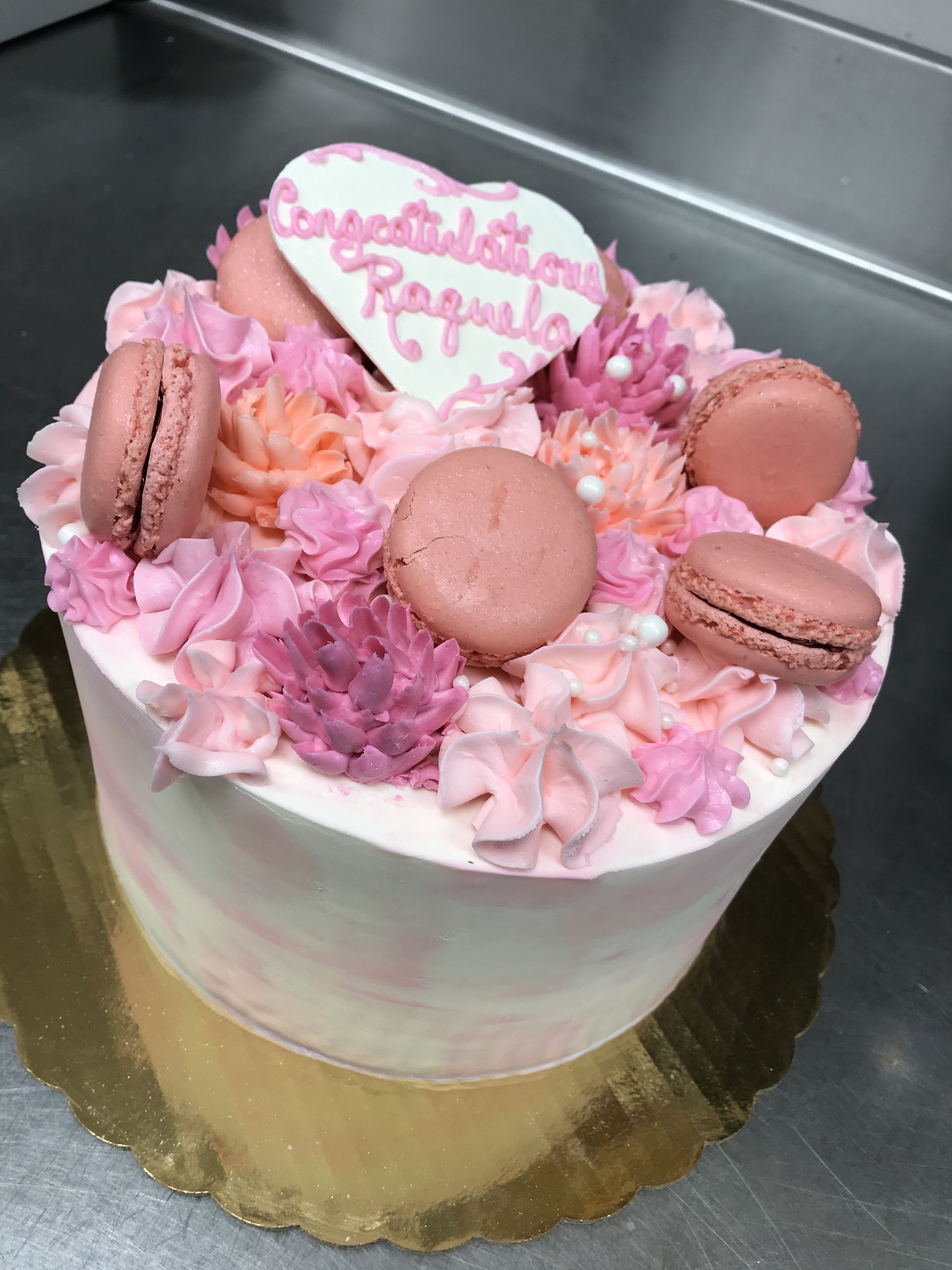 a cake with pink frosting and macarons on it