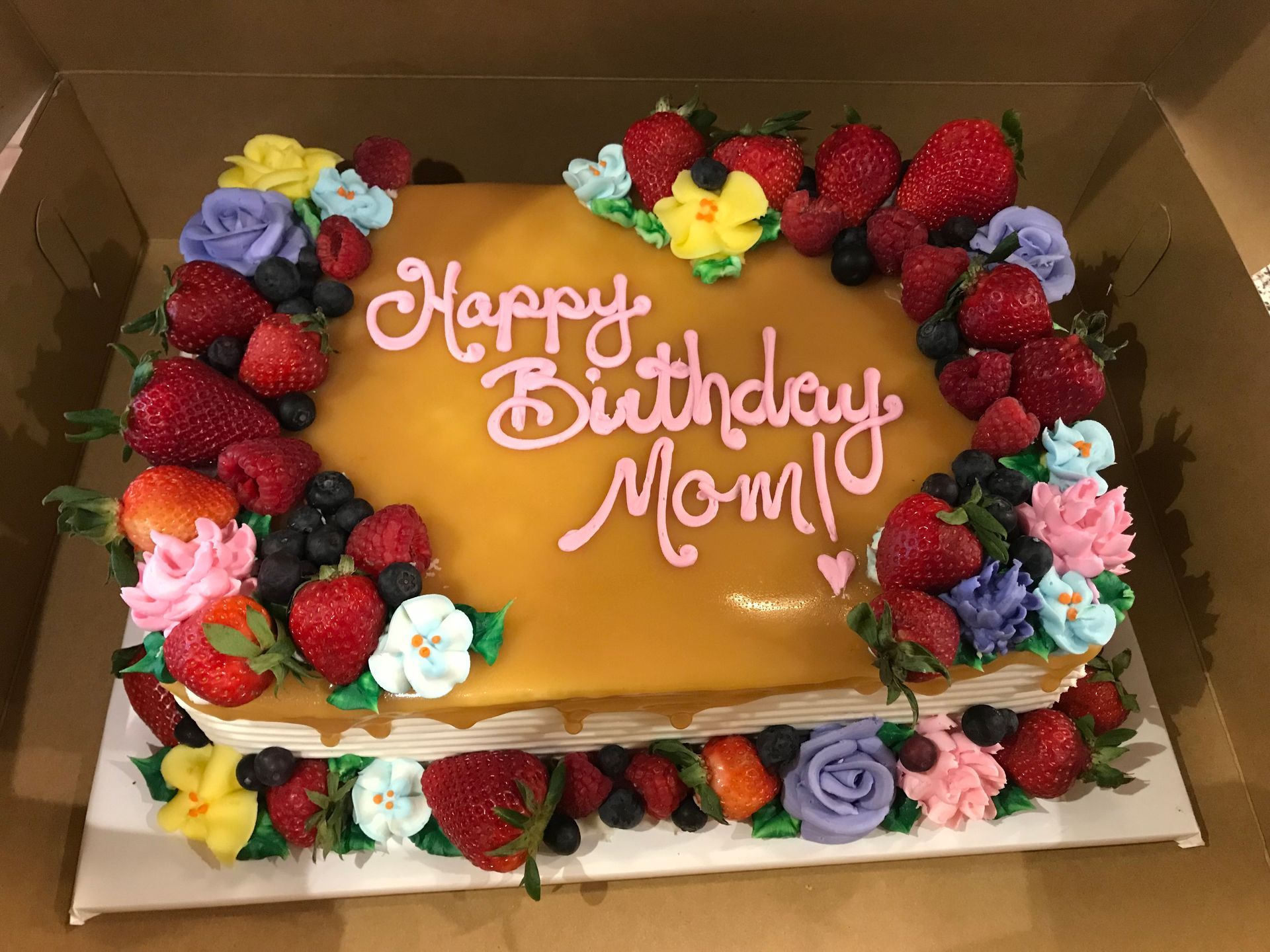 a birthday cake with strawberries and flowers on it