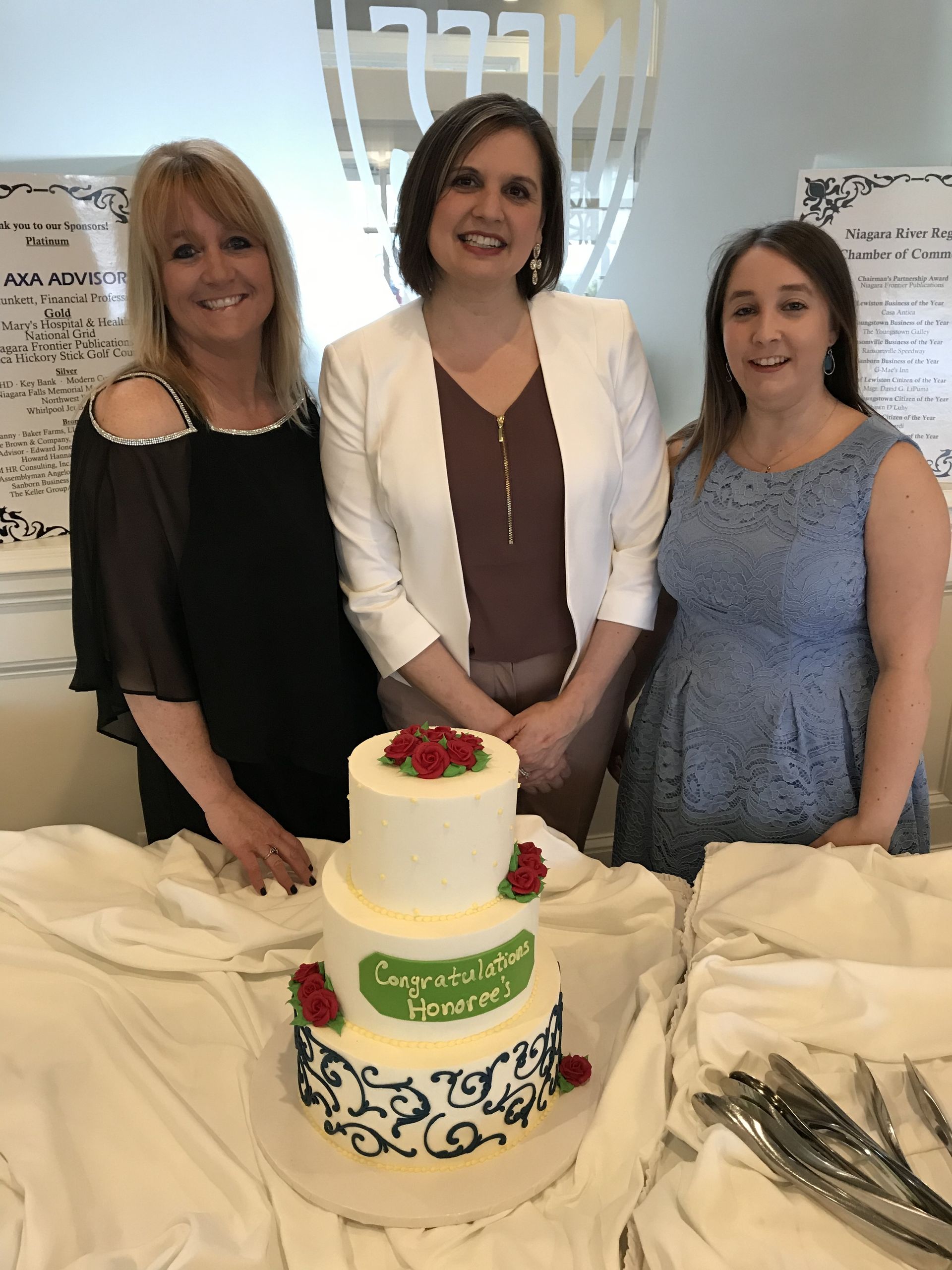 three women are posing for a picture in front of a cake