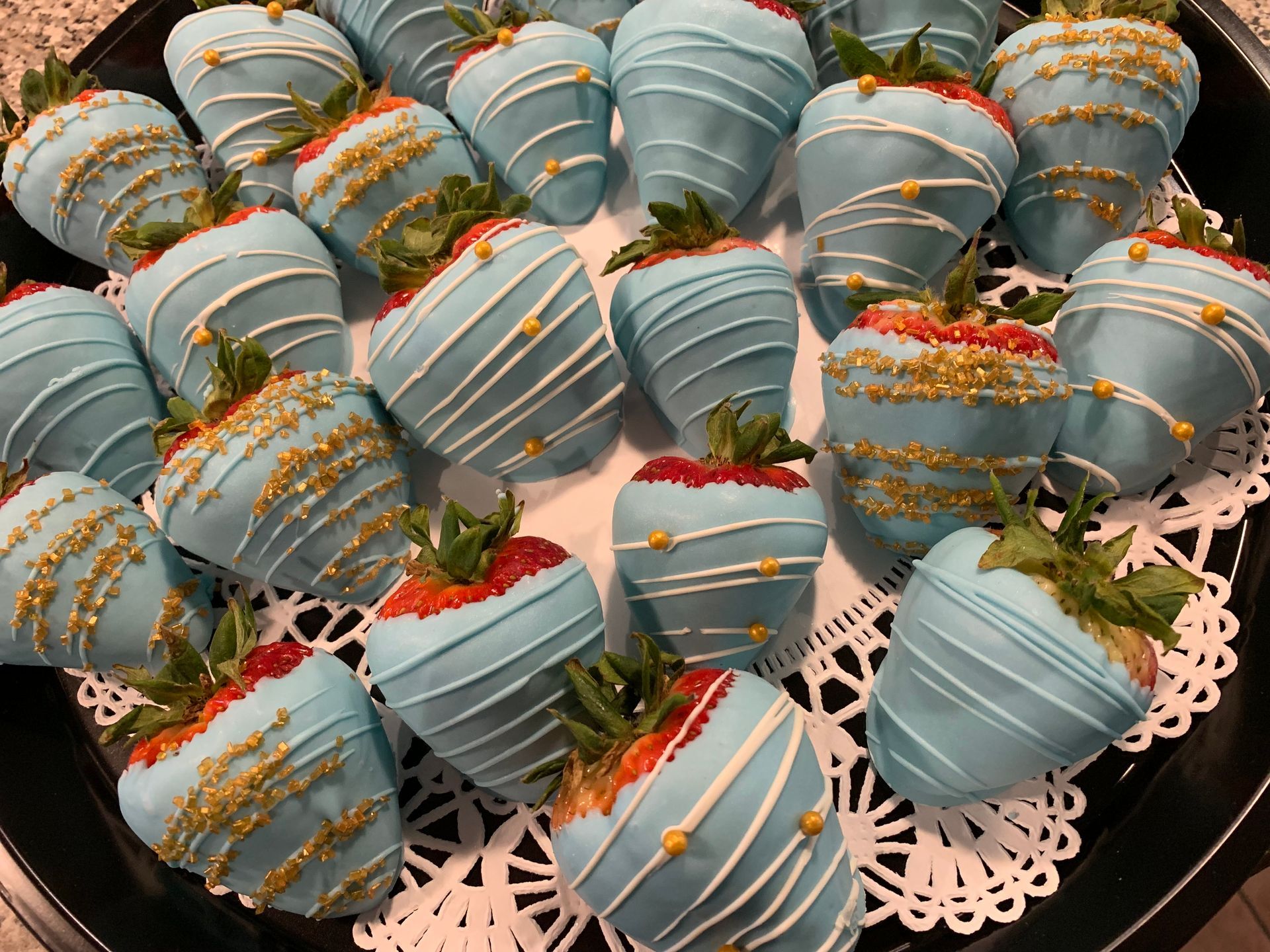 a tray of blue and gold chocolate covered strawberries