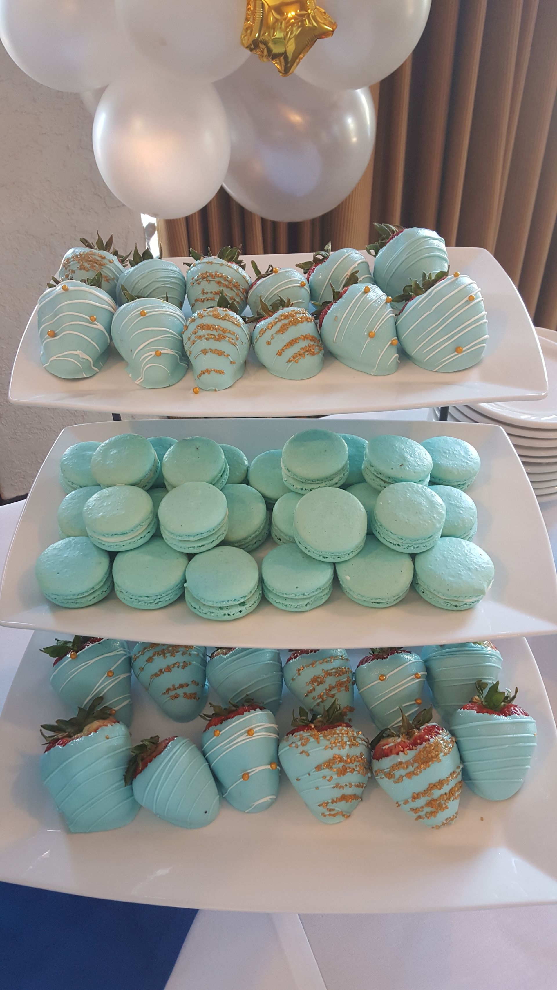 there are three plates of strawberries and macarons on a table .