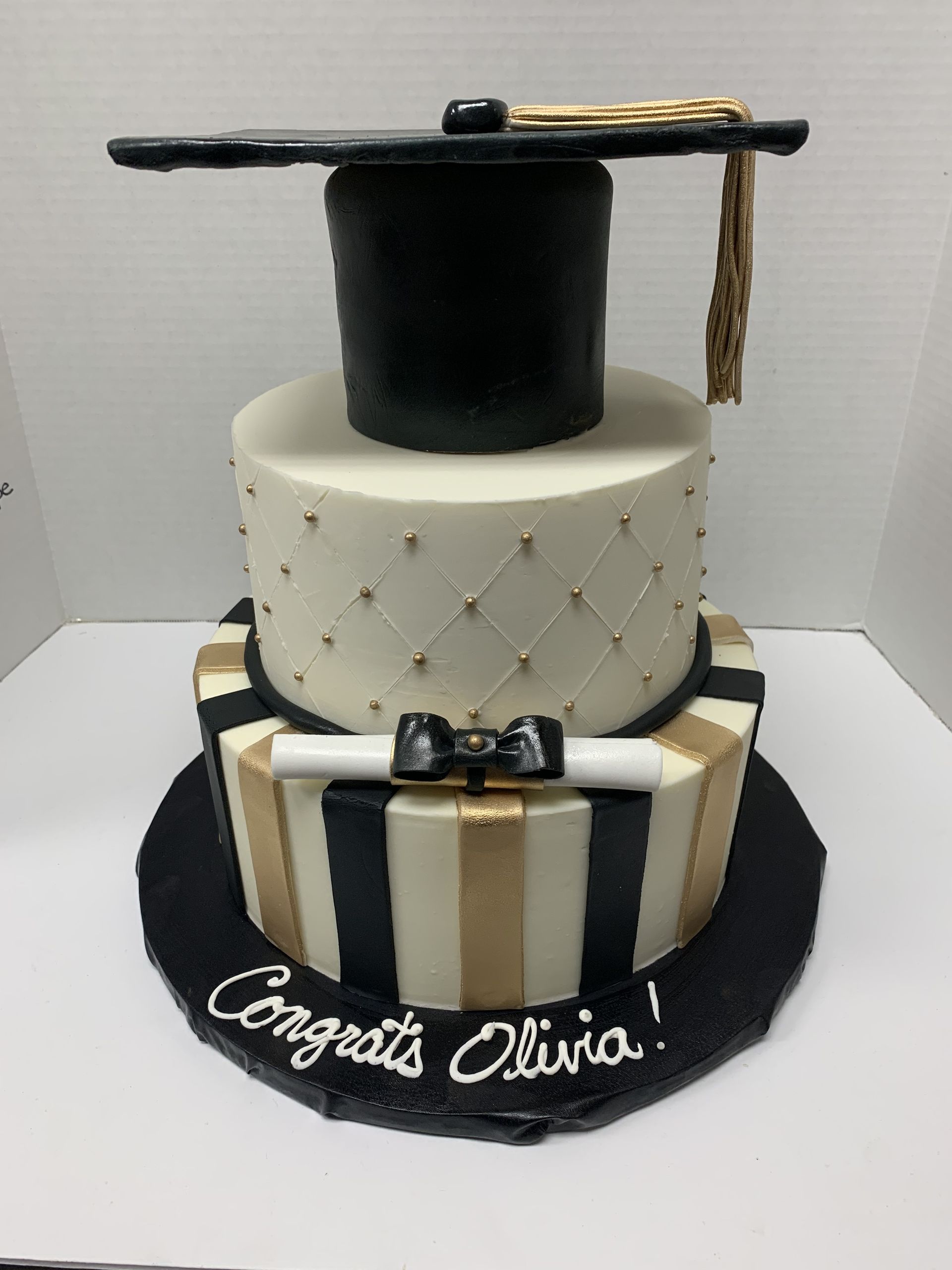a black and gold graduation cake with a graduation cap on top