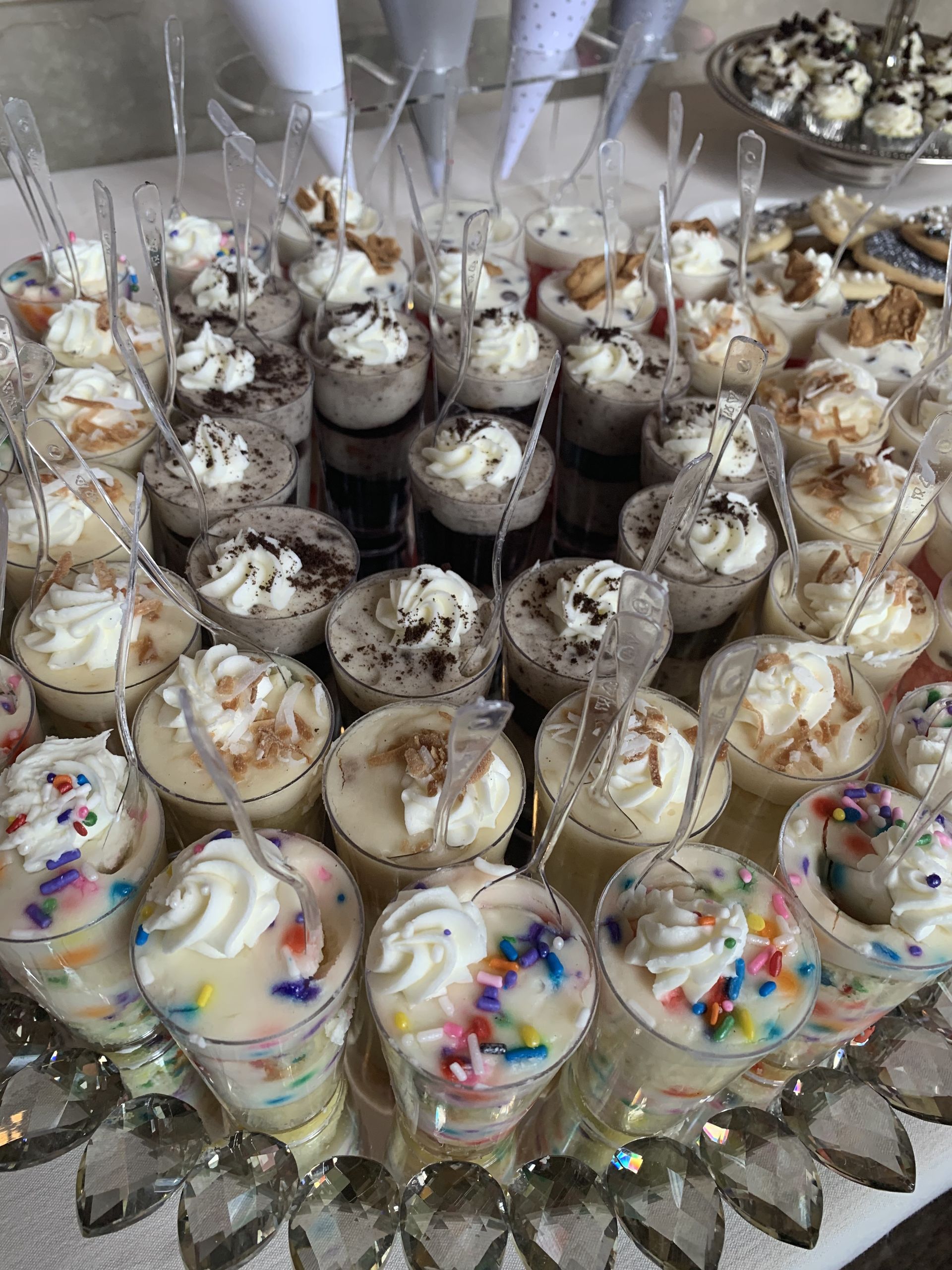 a table topped with a variety of desserts with whipped cream and sprinkles .