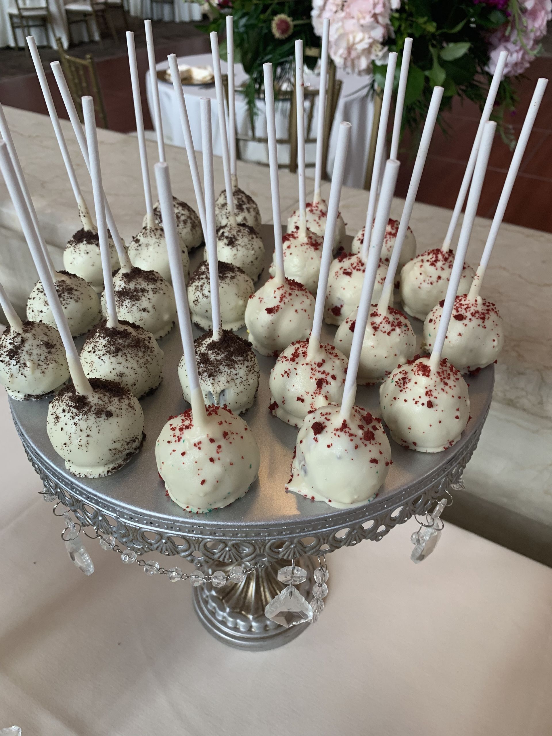 a silver cake stand filled with white cake pops on sticks .