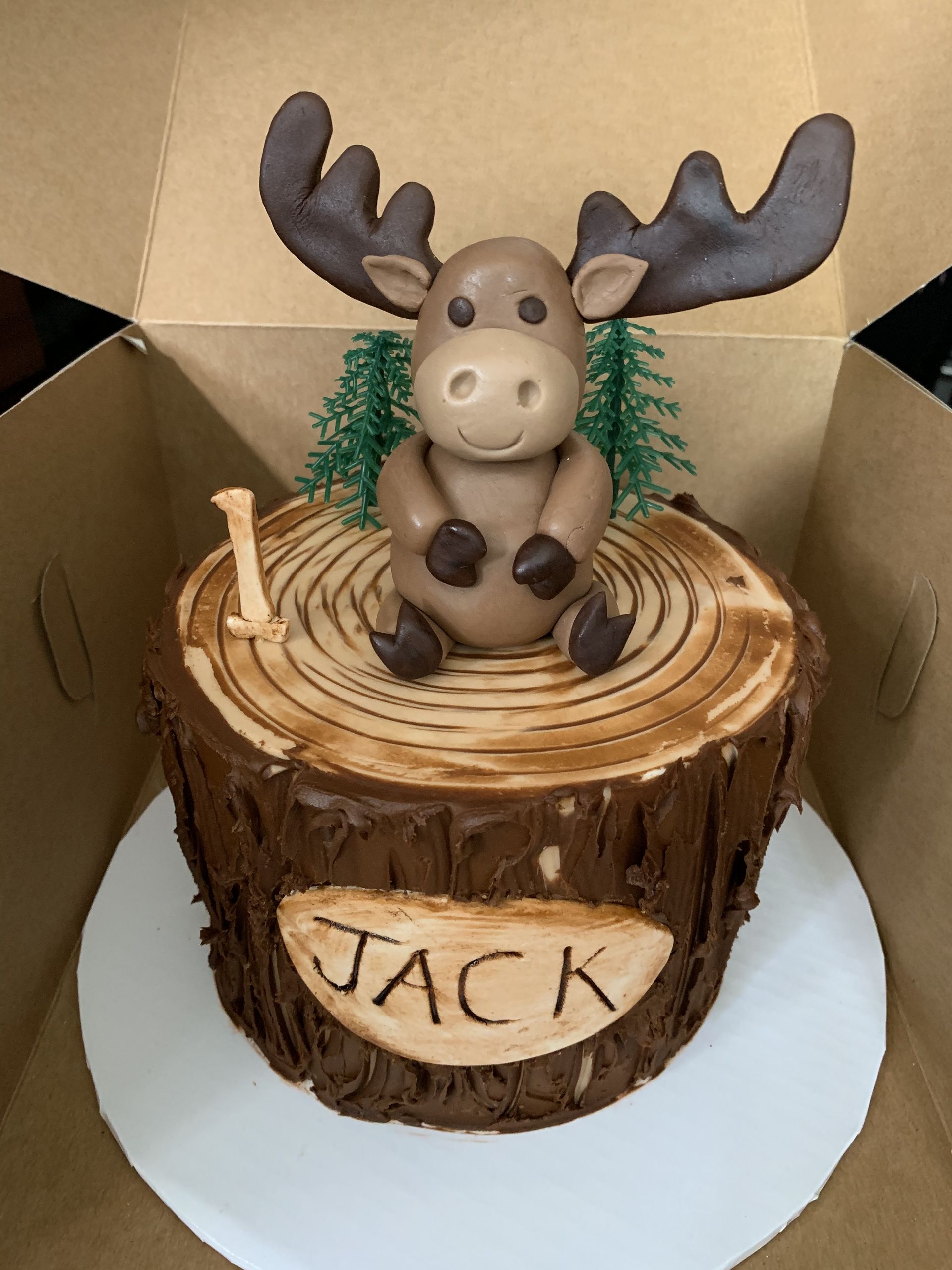 a cake with a moose on top of a tree stump .