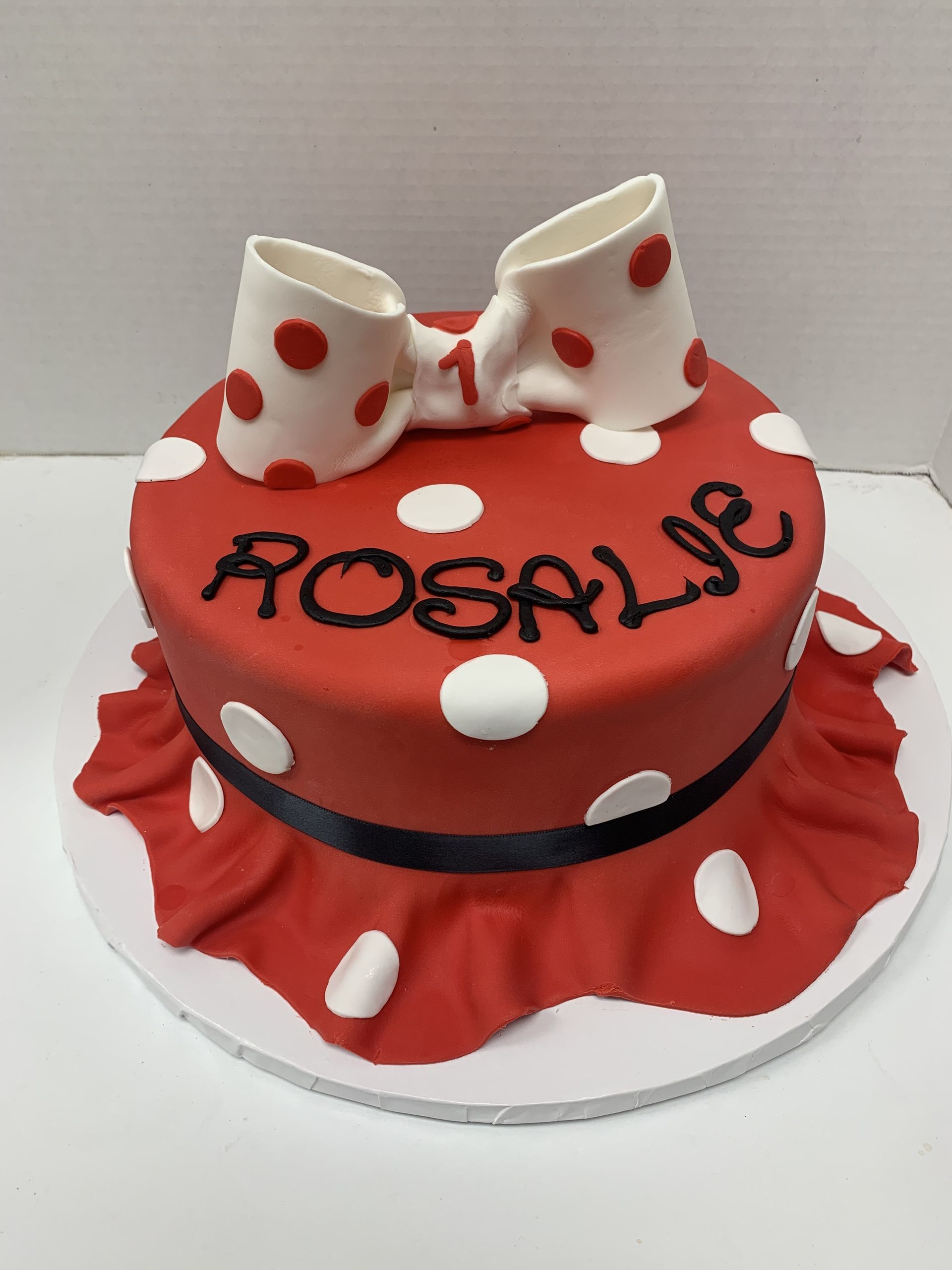 a red cake with white polka dots and the name rosalie on it