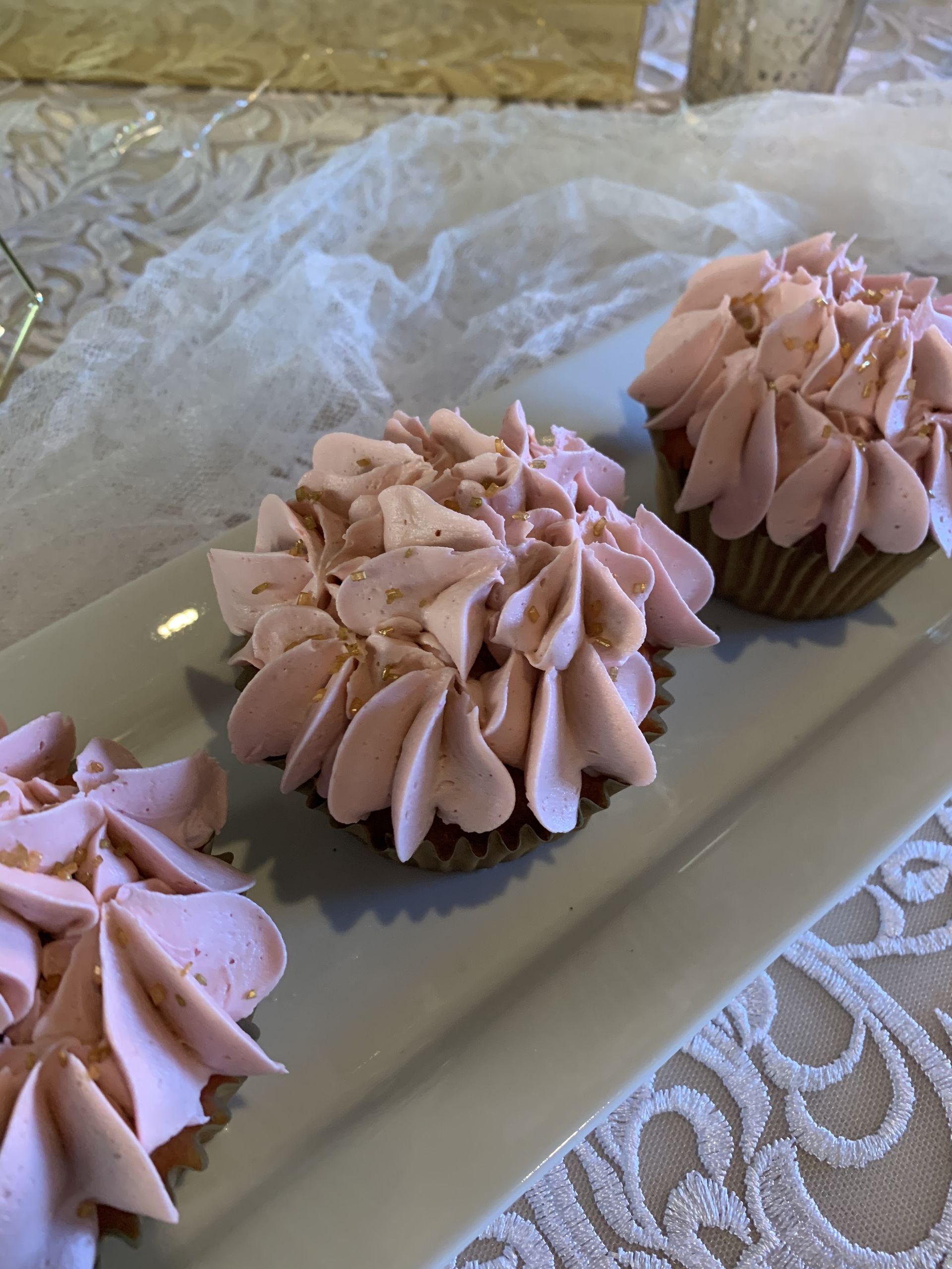 three cupcakes with pink frosting on a white plate