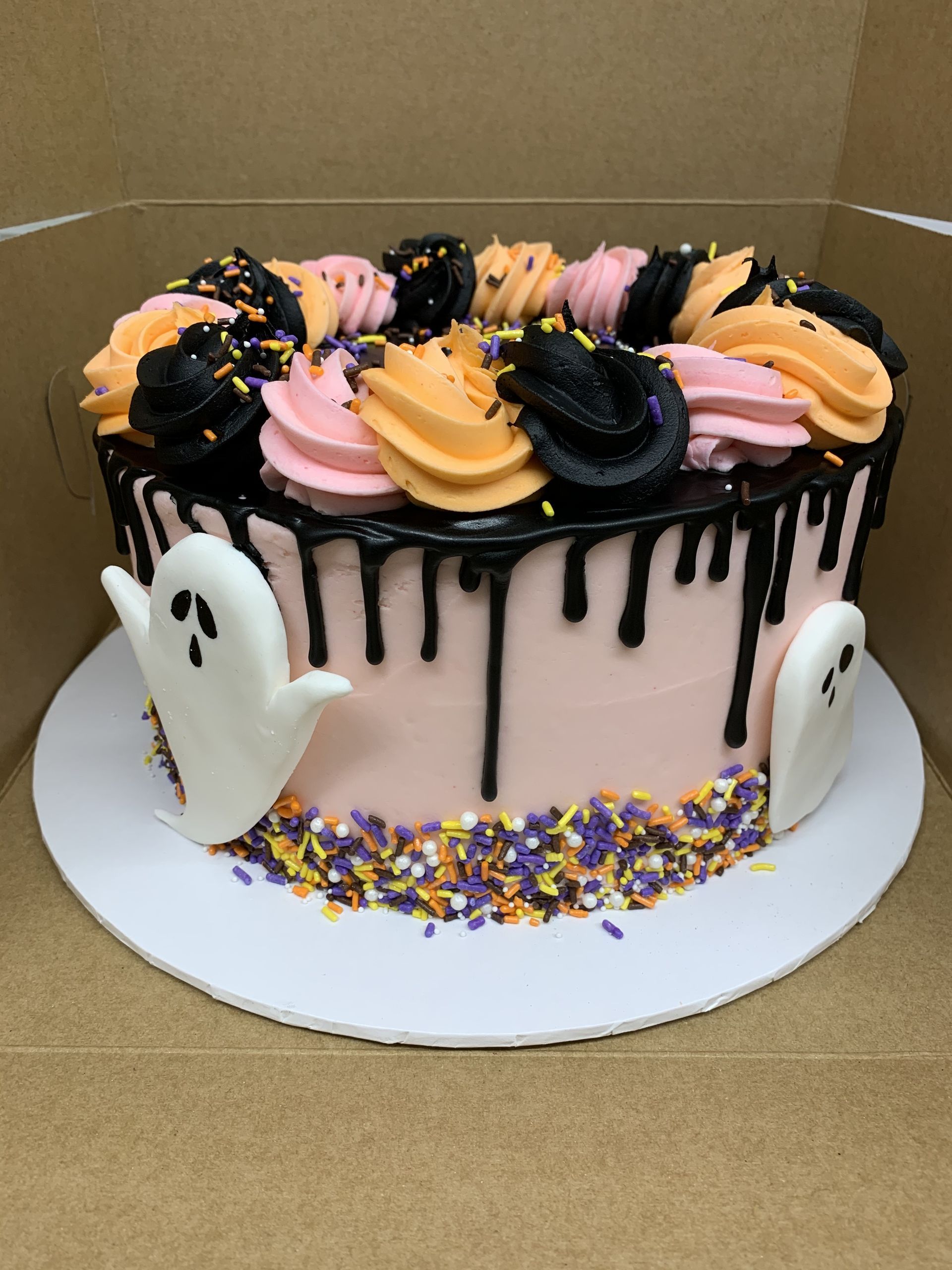 a halloween cake with ghosts and sprinkles on it