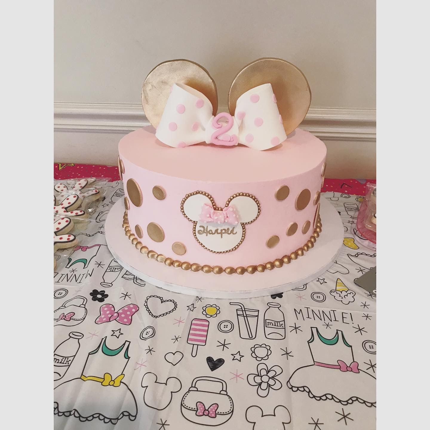 a pink minnie mouse cake with ears and a bow is on a table .