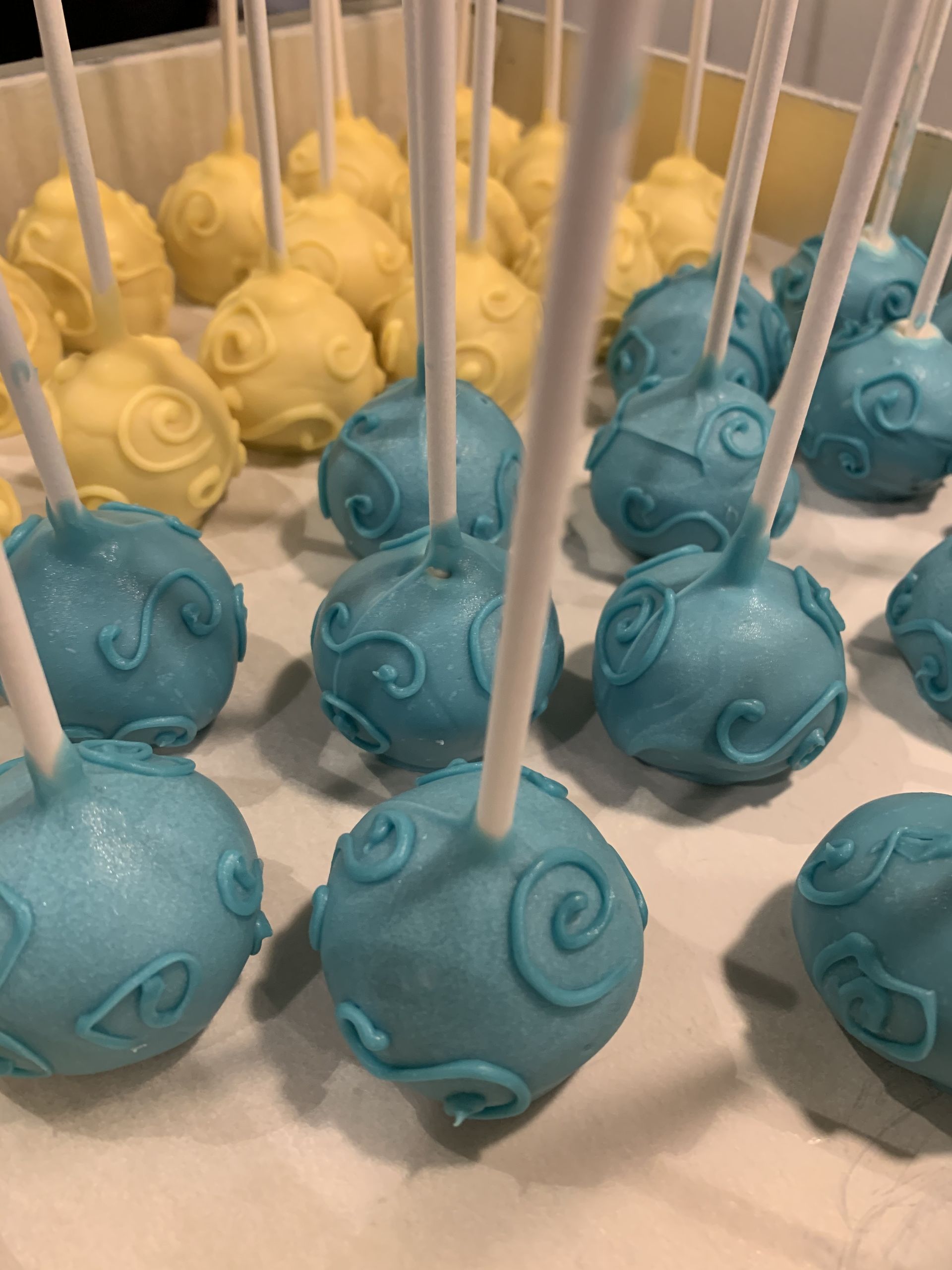 a bunch of blue and yellow cake pops are sitting on a table .