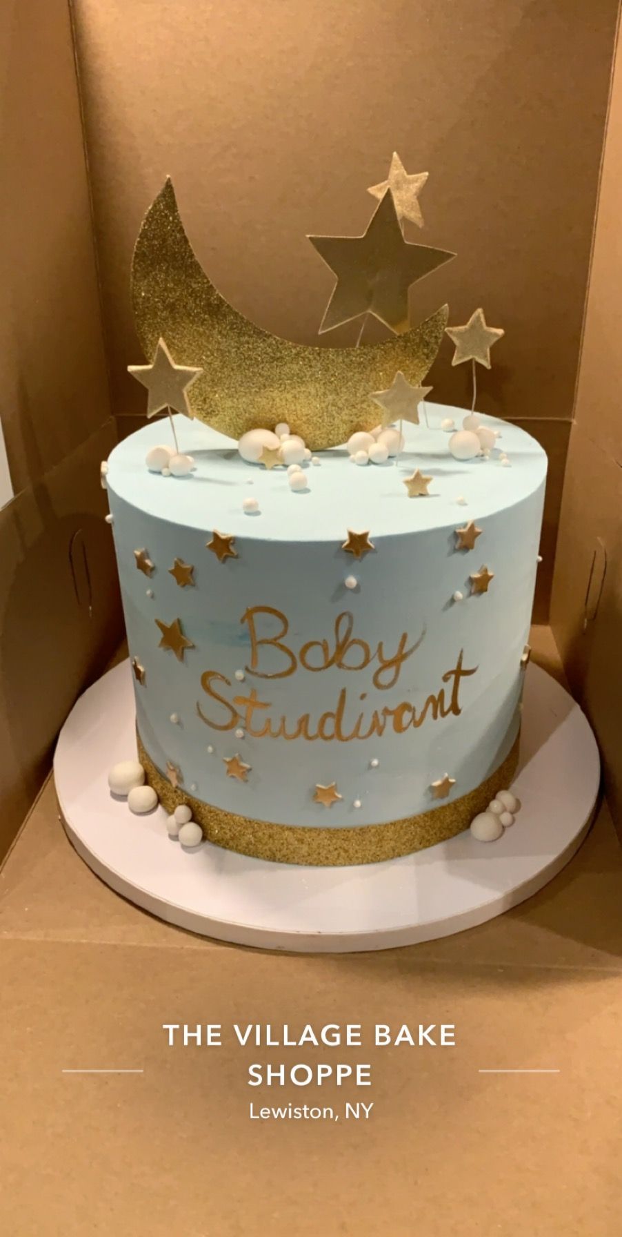 a baby shower cake with a crescent moon and stars on top .