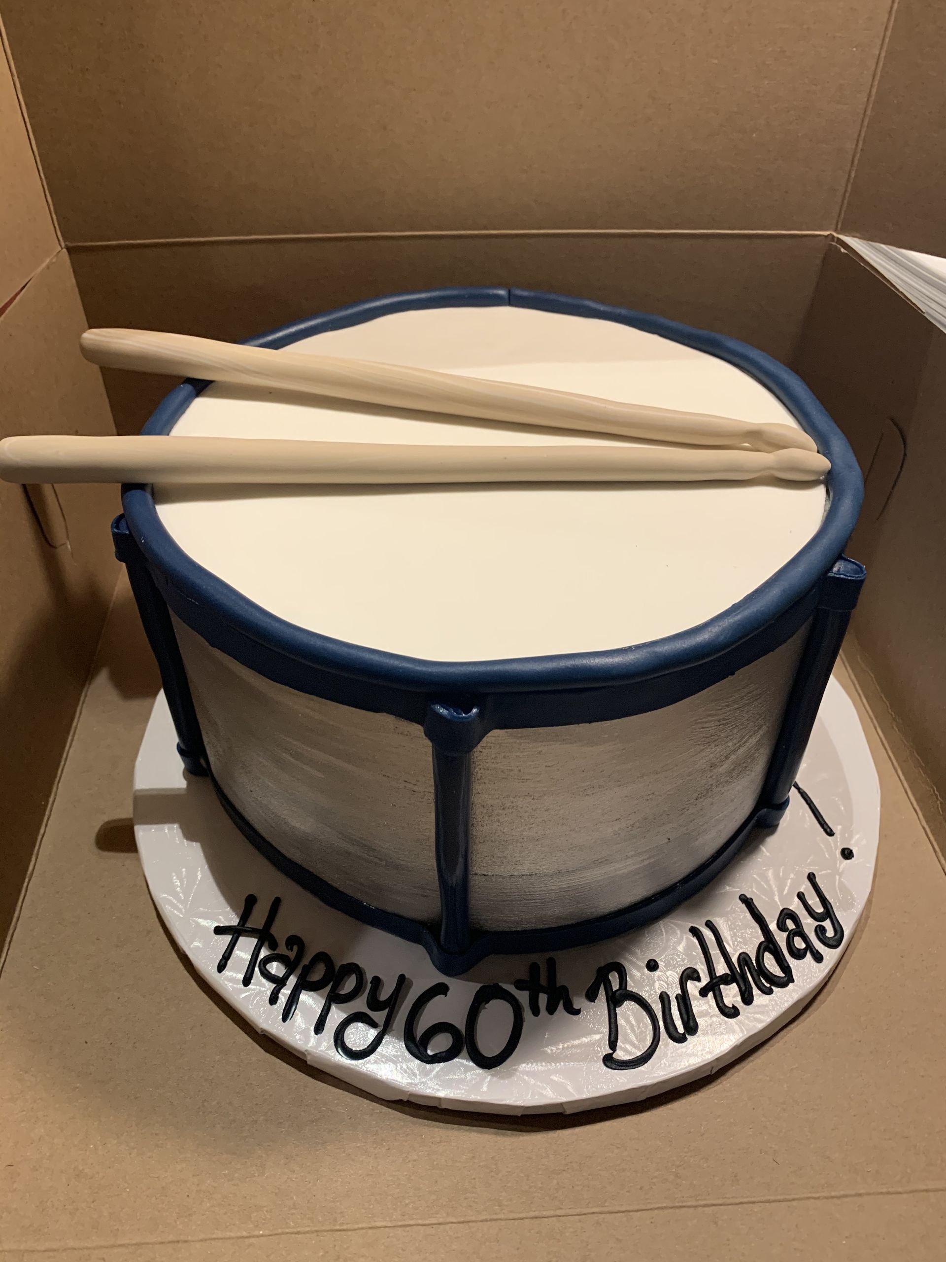 a birthday cake in the shape of a drum with drumsticks on it