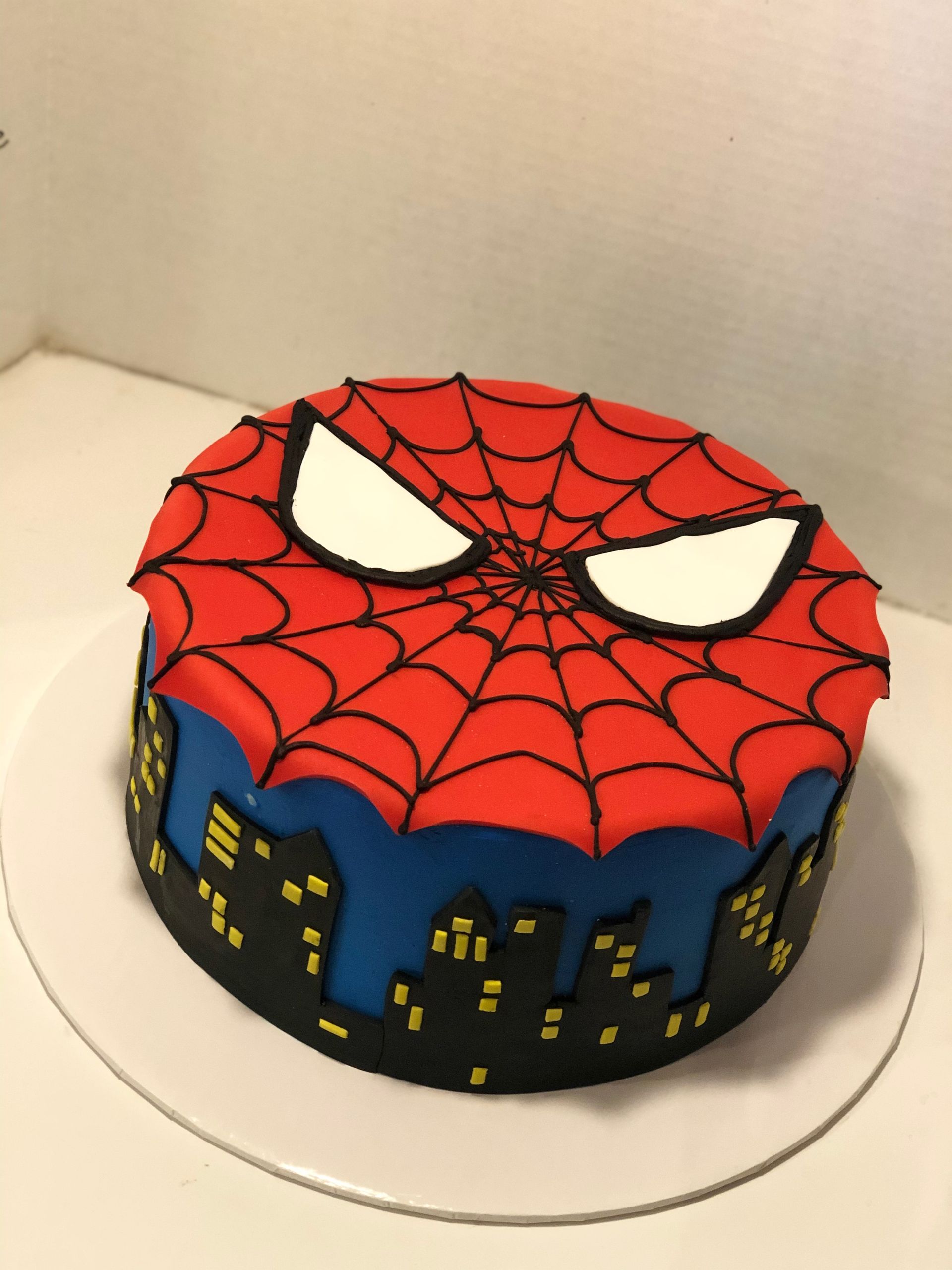 a spiderman cake with a city in the background