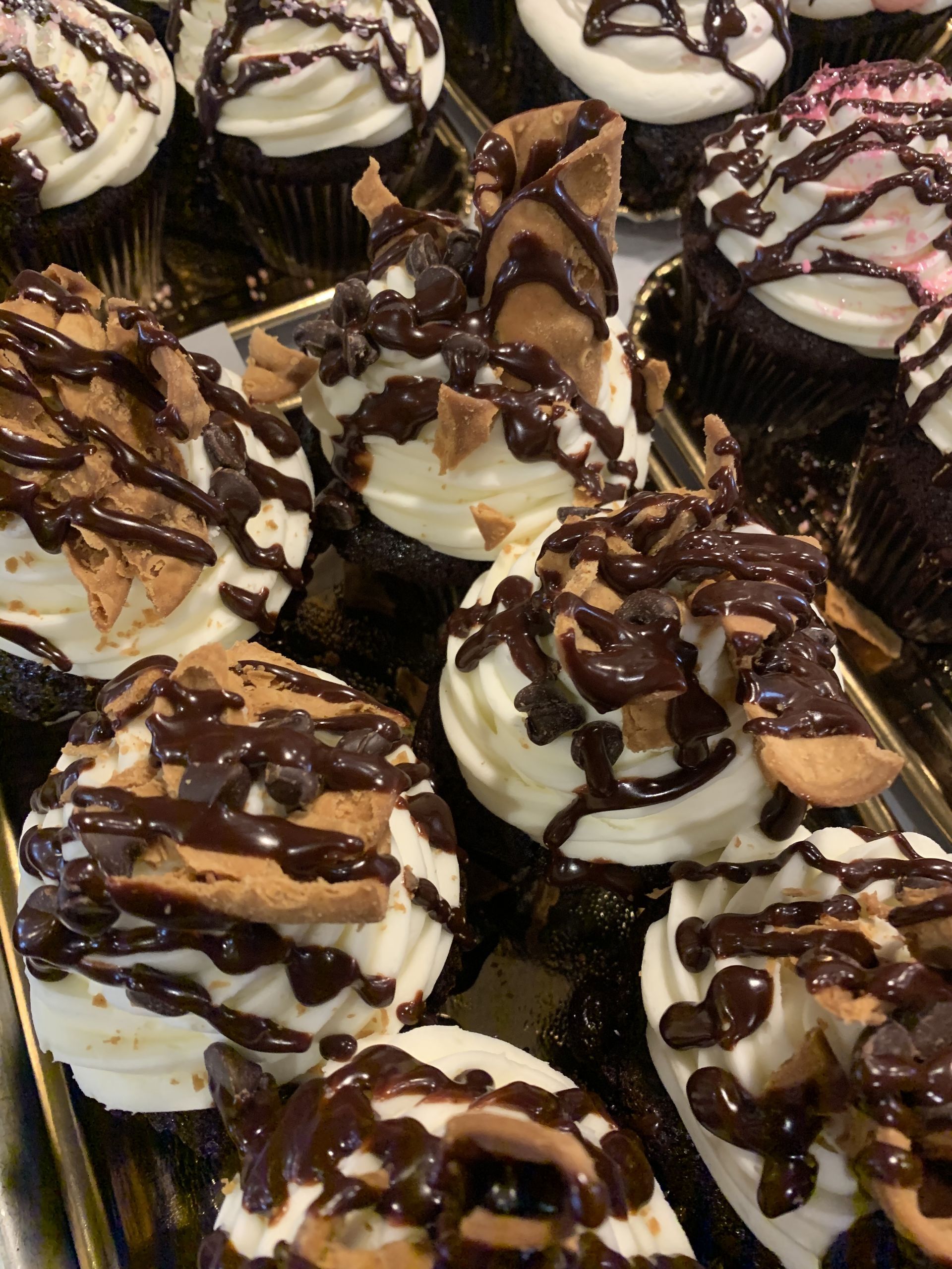 a tray of cupcakes with chocolate frosting and cookies on them .