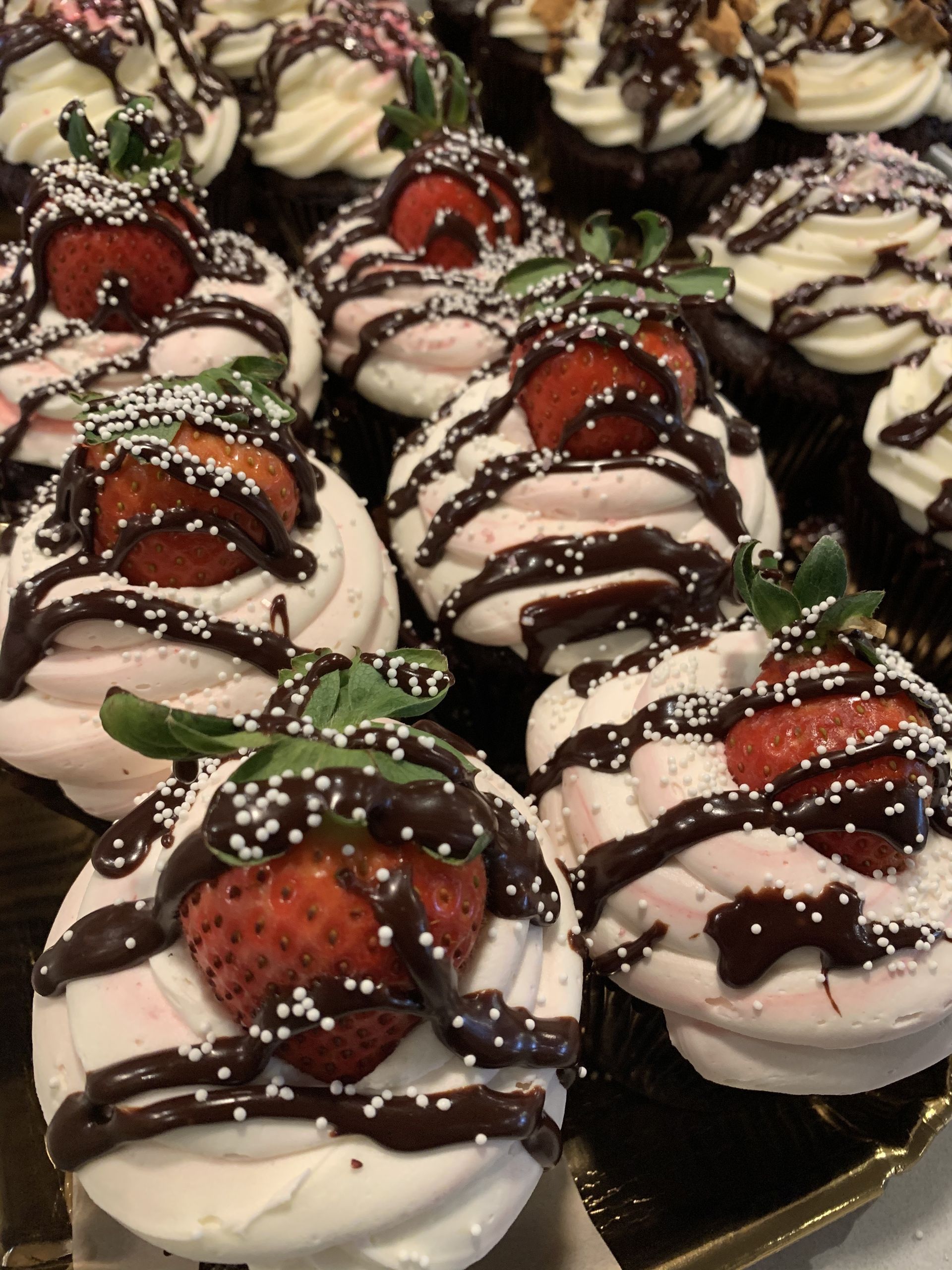 a bunch of cupcakes with strawberries on top of them