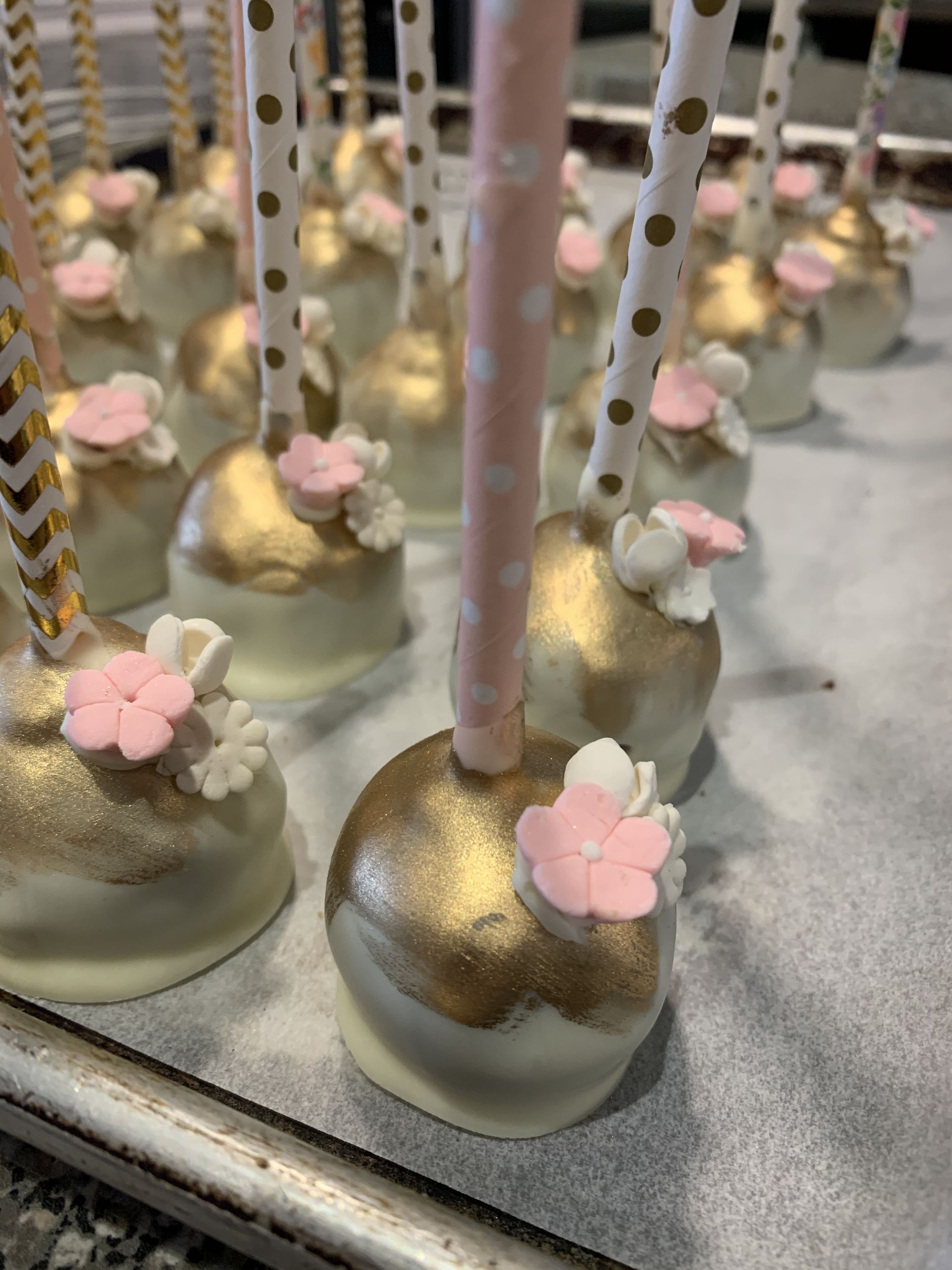 a bunch of cake pops with pink flowers on them are sitting on a table .