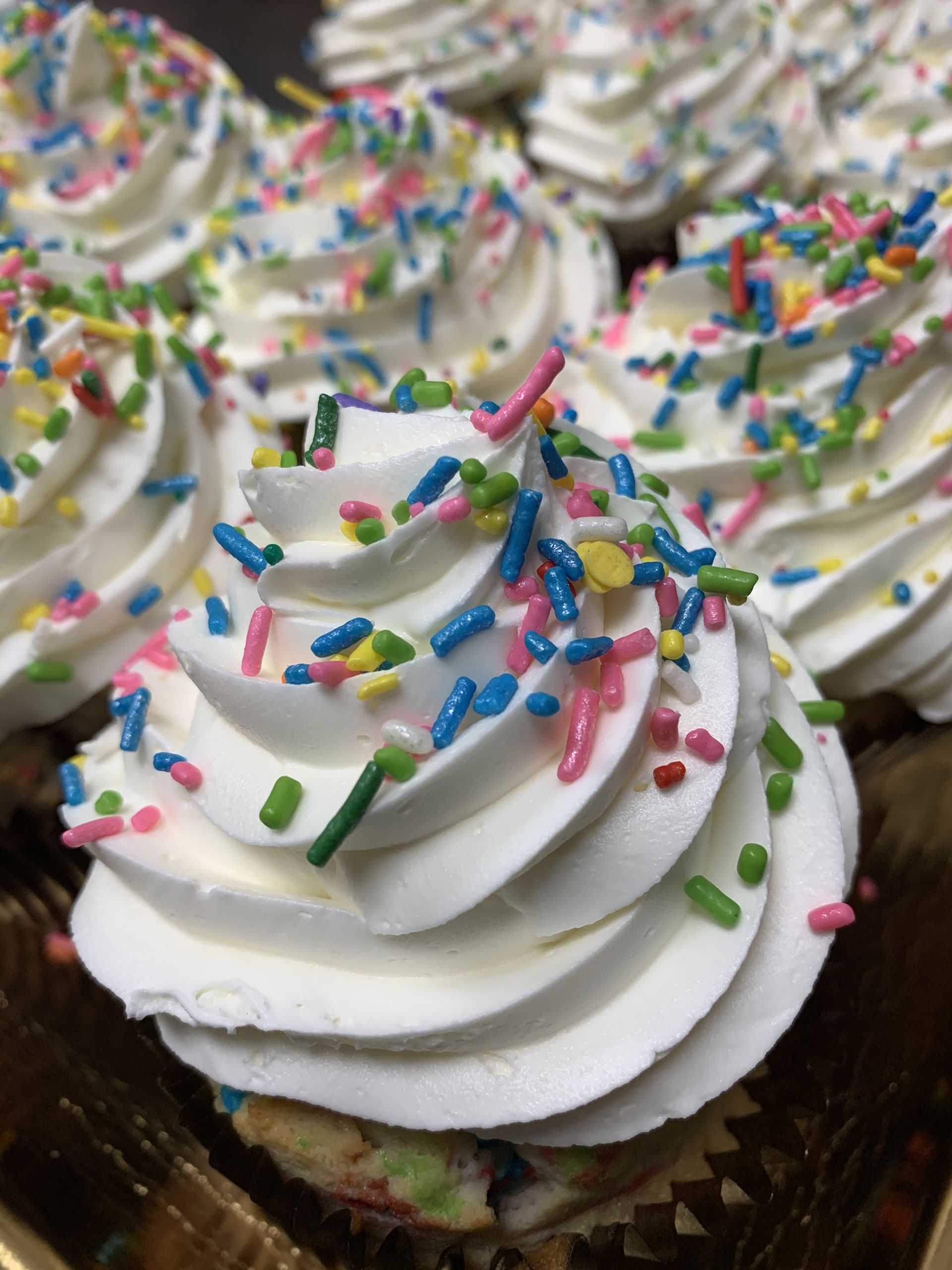 a close up of a cupcake with whipped cream and sprinkles .