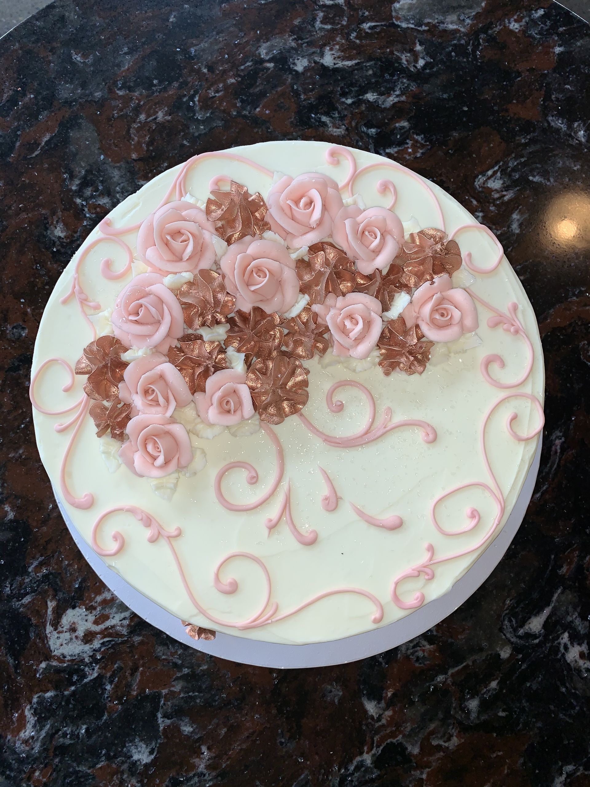 a white cake with pink roses and swirls on it