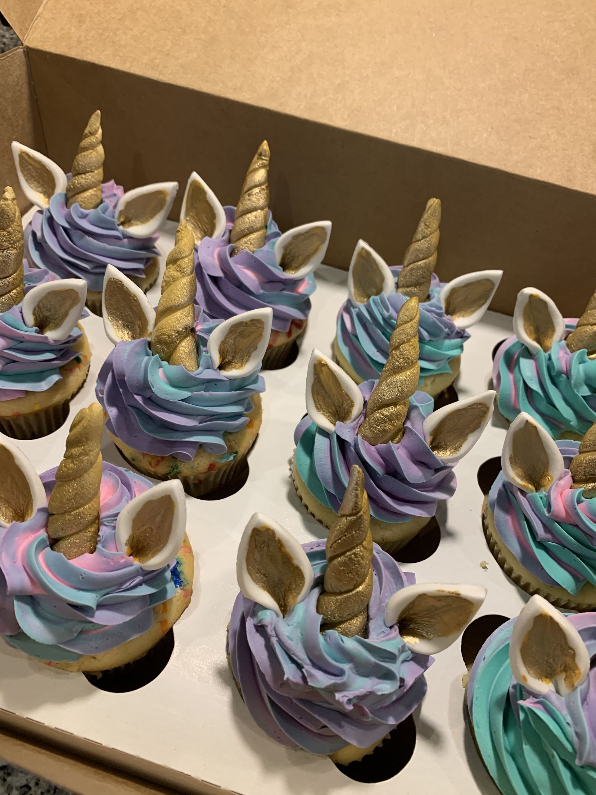 a box of cupcakes decorated to look like unicorns .